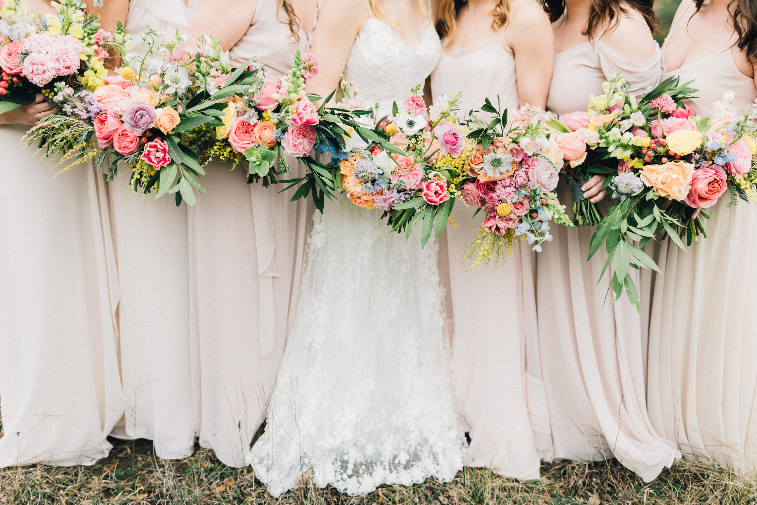  Bohemian style, colorful bridal and bridesmaid bouquets with pink, yellow, coral peonies, poppies, anemone, spray roses, ranunculus at Addison Grove. Petal Pushers floral event design studio located in Dripping Springs, Texas. 