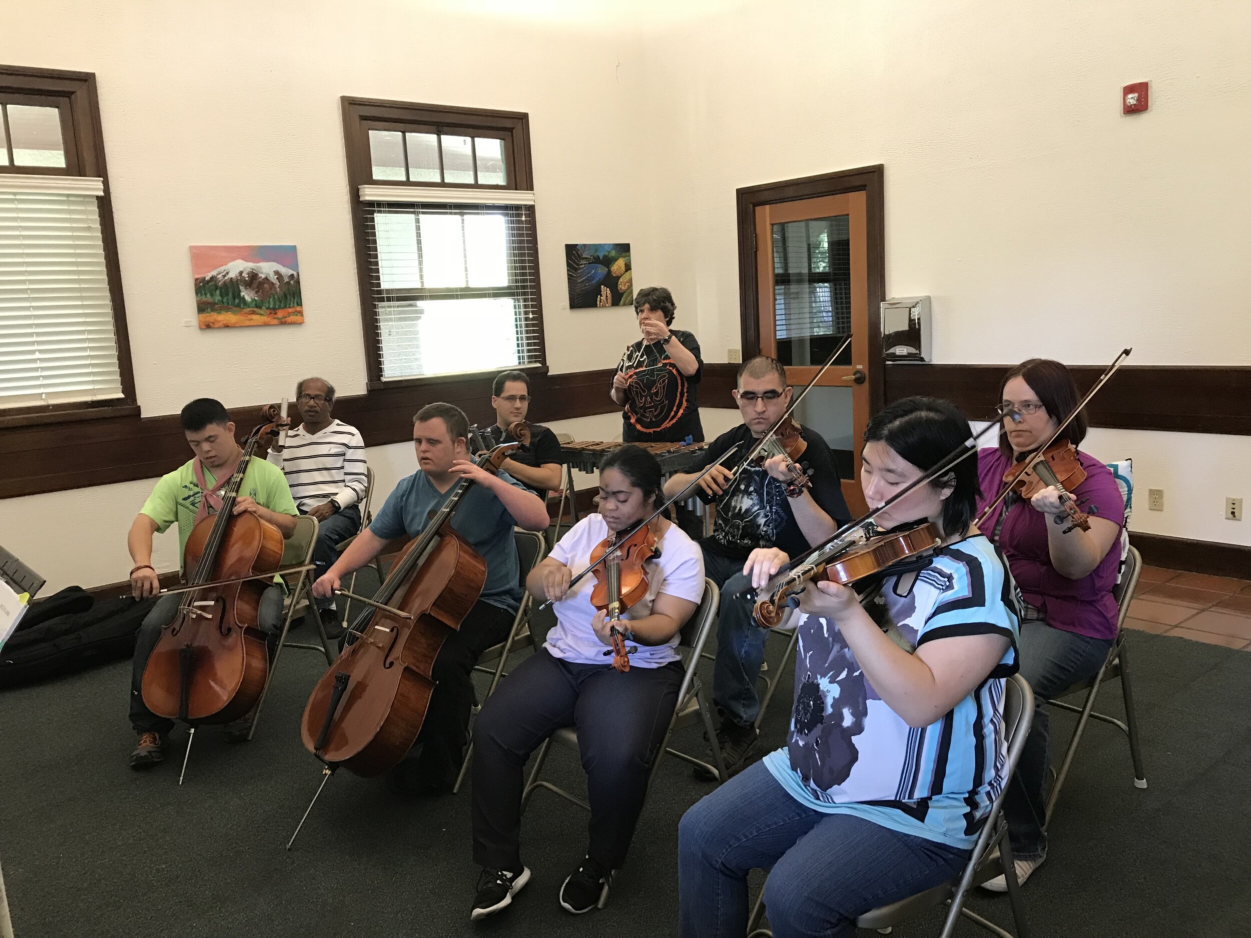  Participants playing in a group with a variety of instruments. The instruments included in this group are cellos, violins, and xylophones.  