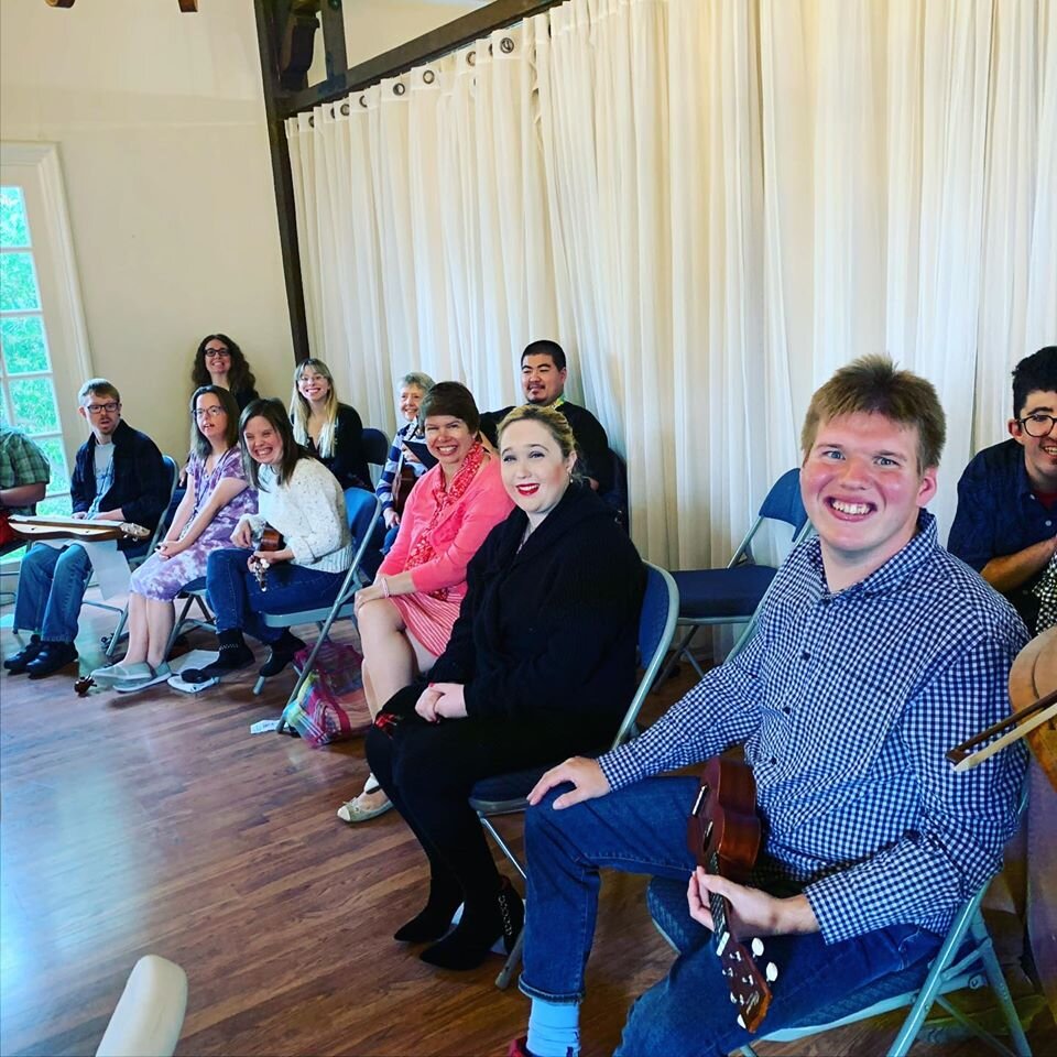  Participants seated in their ensemble, featuring instruments such as ukuleles.  