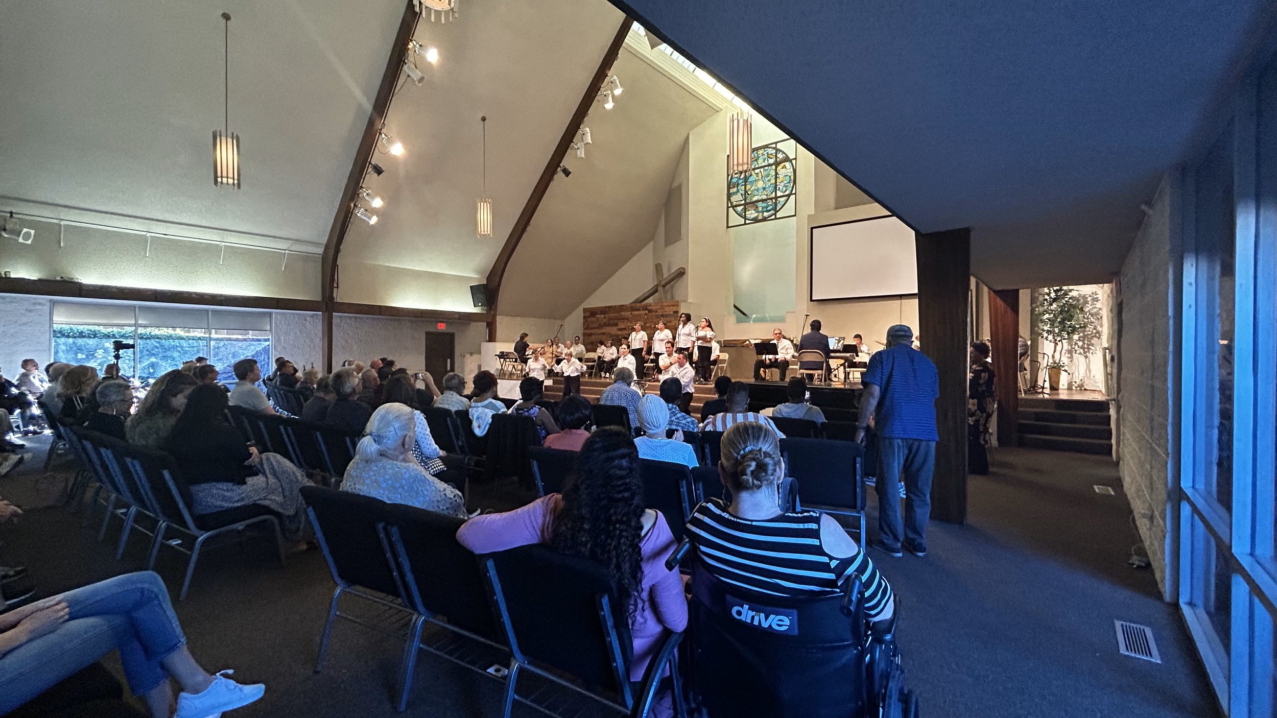  Creative Identity Anaheim participants singing and playing instruments for their 2023 Summer Concert and Boutique called “Coming Together as a Community” to an audience of attendees. 