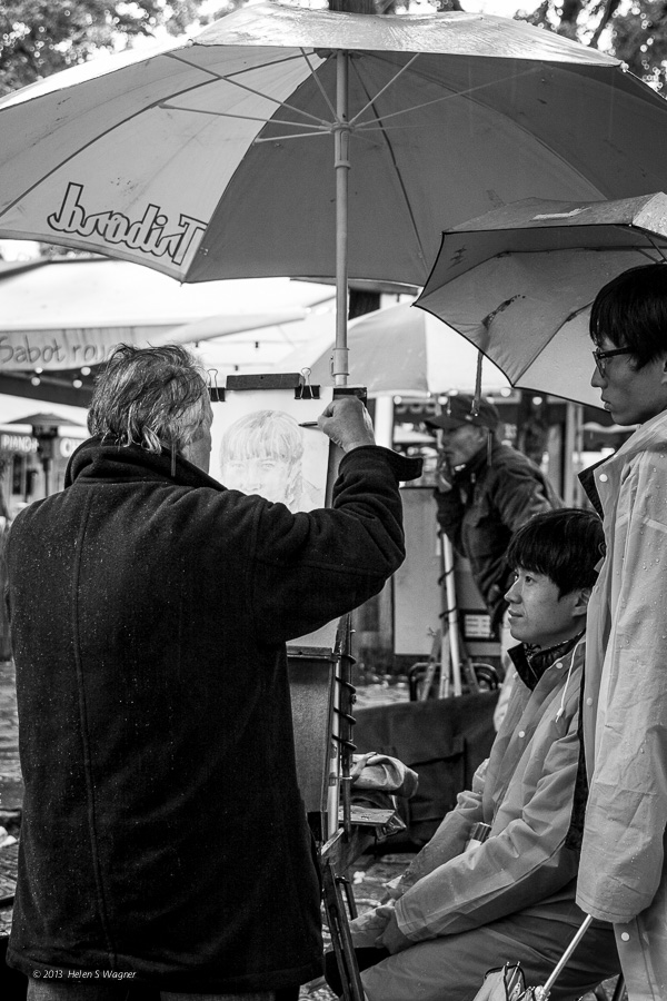 An artist at Place du Tetre drawing a portrait of a visitor.