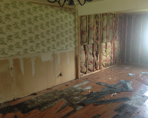 As you can see here, the wood paneling in the living room and the wainscoting in the dining have been removed and the vinyl flooring is in the process of being pulled up.