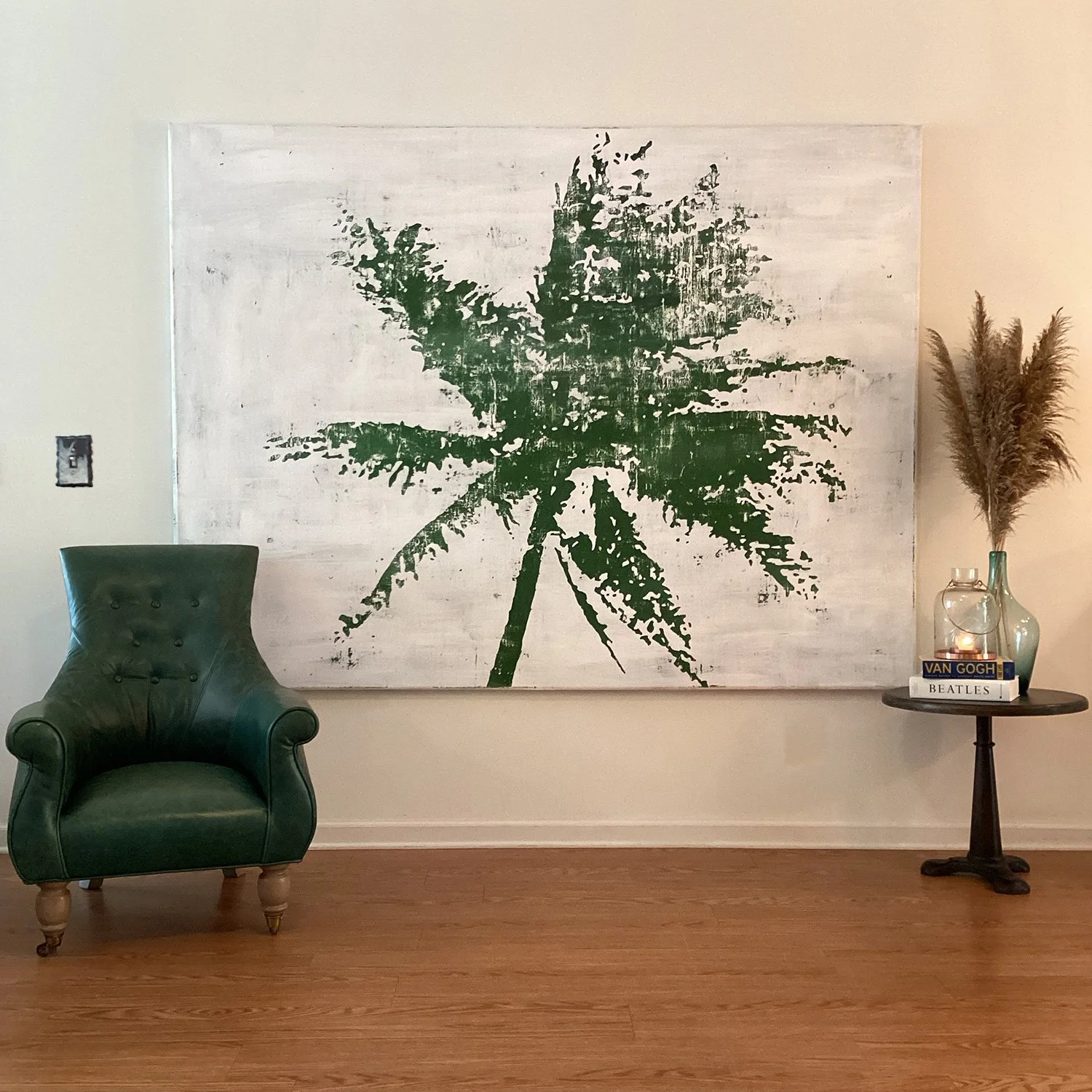 Hollis Brown Thornton painting of a tree installed above a green chair in a gallery setting, with additional objects arranged beside the work.