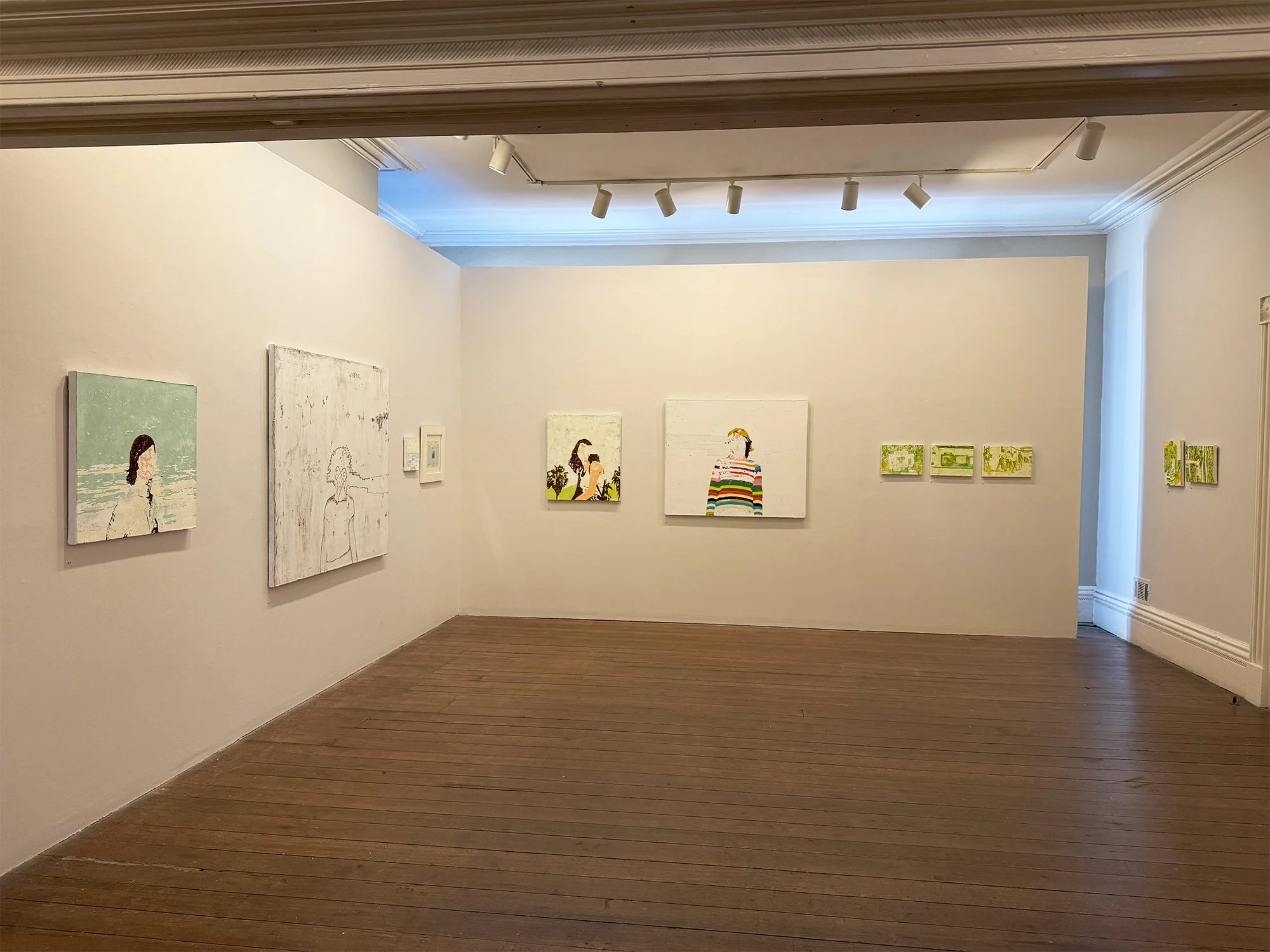 Art gallery with paintings of women and landscapes on white walls, wooden floor, and track lighting.