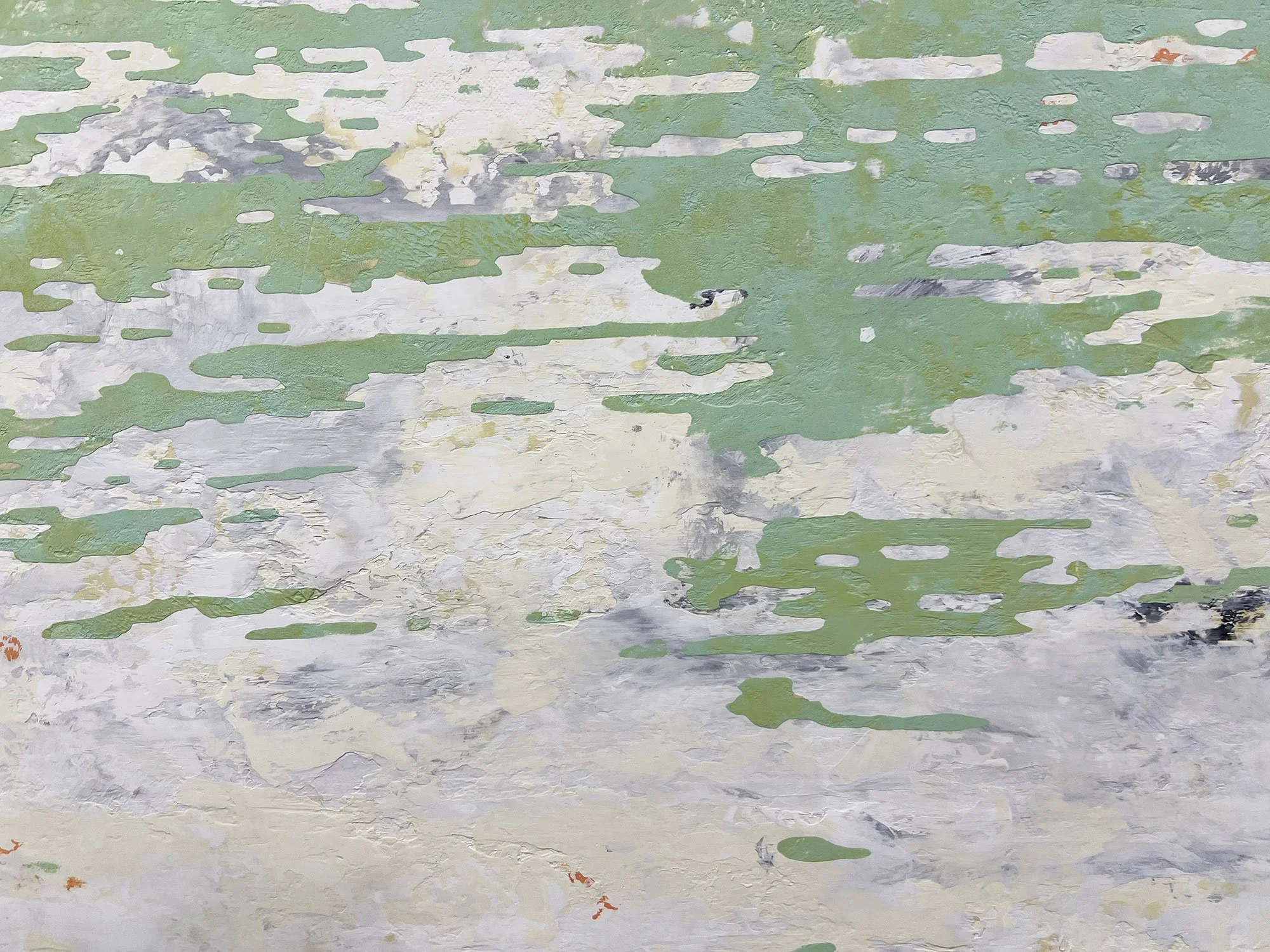 Close-up of a weathered wall with peeling green, white, gray, and black paint.