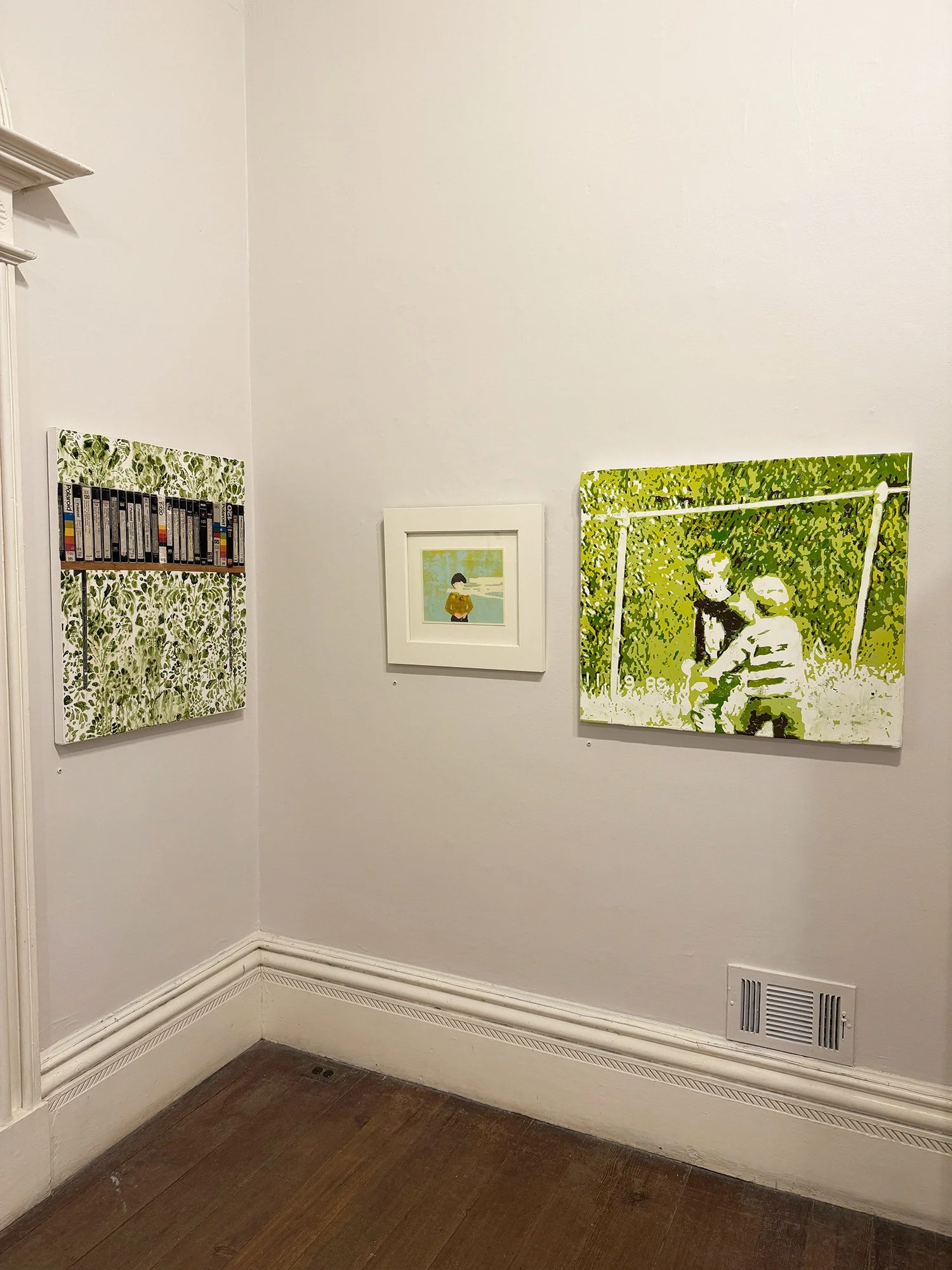 Three framed art pieces hung on a white wall in a gallery. The left artwork features a green and black pattern with books, the middle depicts a woman with short hair looking away, and the right shows two children on a swing in greenery, rendered in a