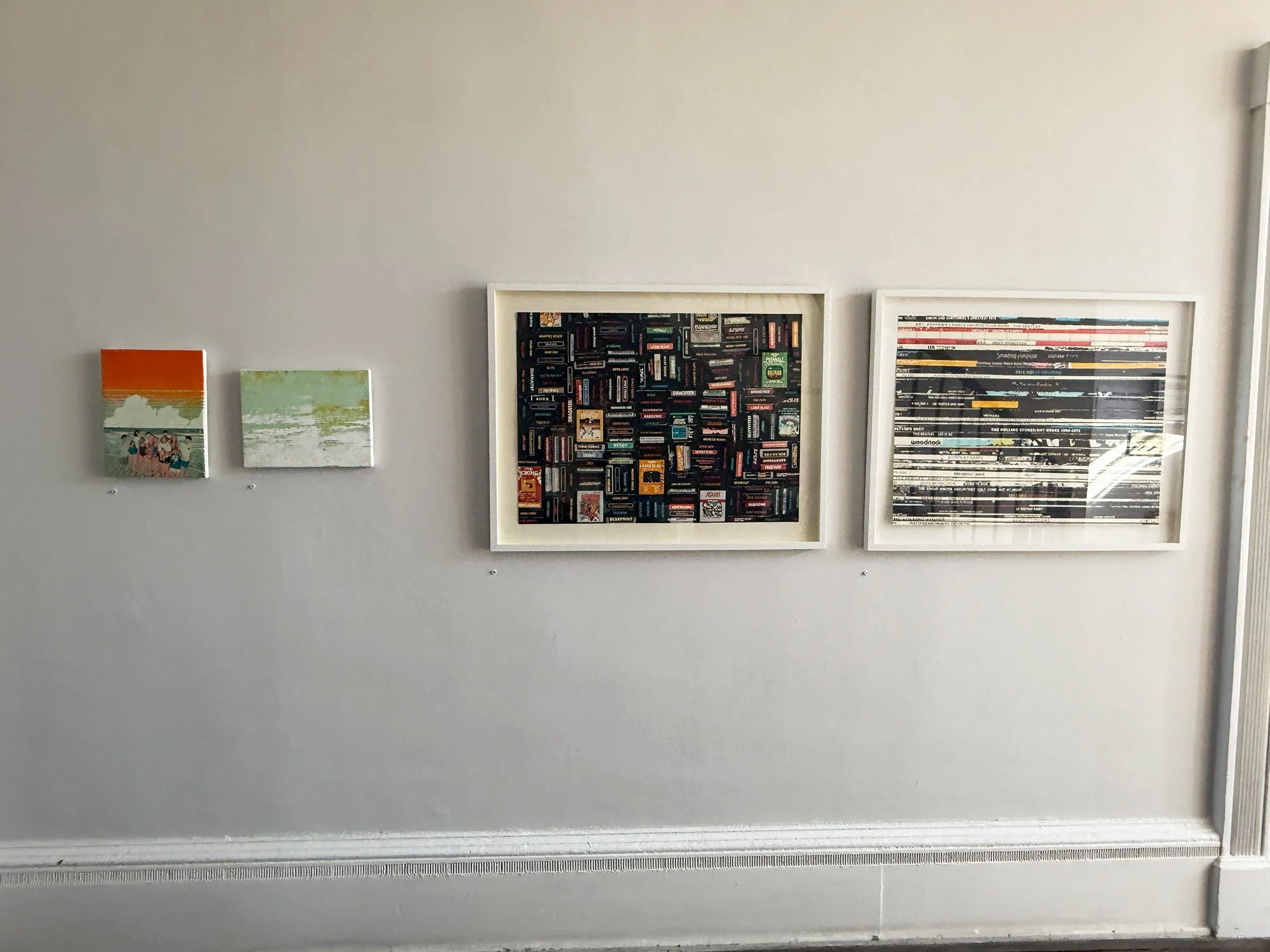 Five framed pieces of artwork hung on a white wall, including two small beach scenes on the left and three larger images, two of which feature abstract or patterned designs.