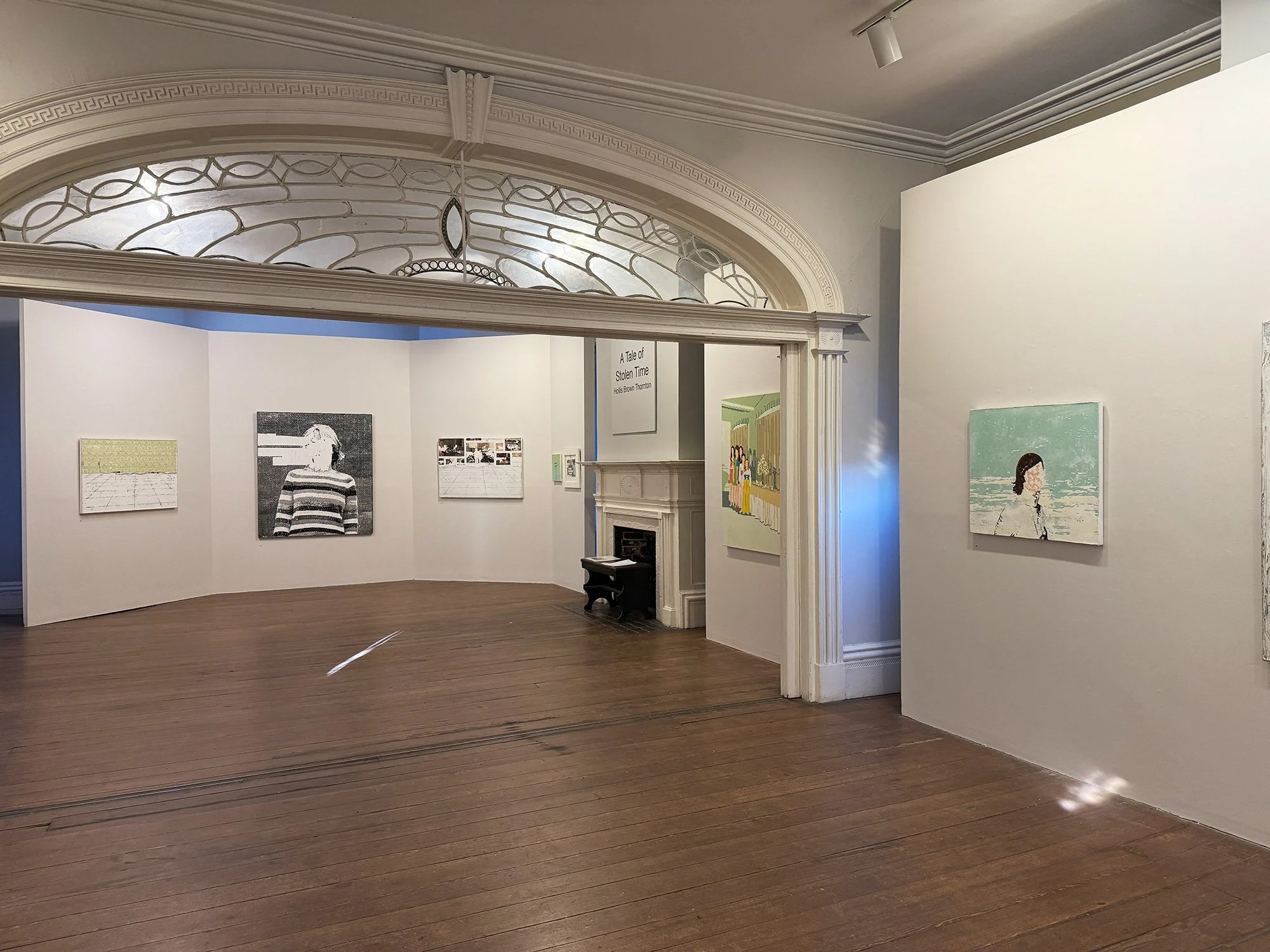 Art gallery with white walls, wooden floor, and paintings displayed on the walls. An ornate window above the entrance, a fireplace, and a sign reading 'A Tale of Silent Time' are visible.