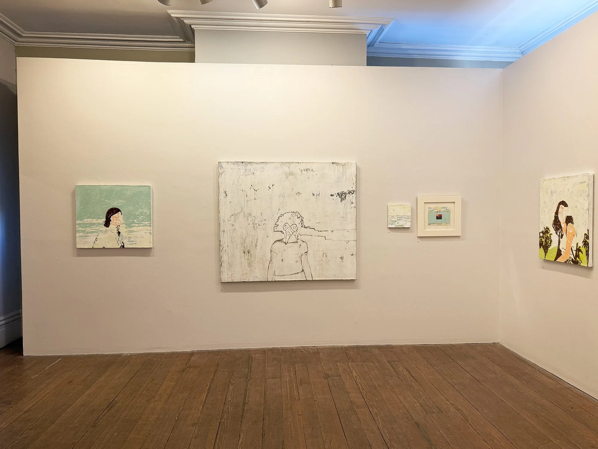 Gallery wall with five small paintings, including portraits and abstract art, displayed in an art gallery with wooden floors and crown molding.