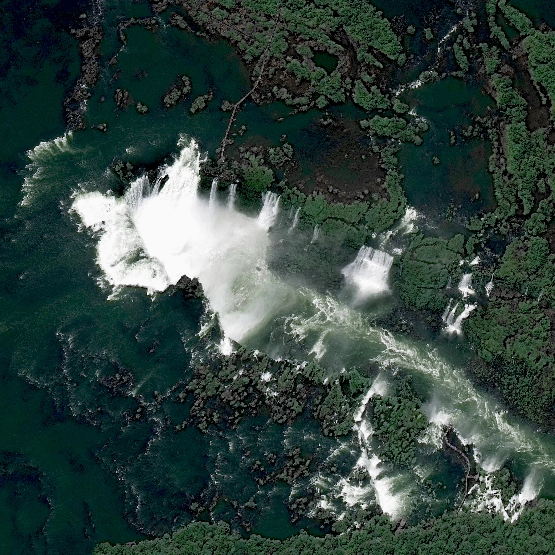 Iguazu Falls, the largest waterfall system in the world, is located on the border of Argentina and Brazil. Approximately half of the Iguazu River flows into a long and narrow chasm called the Devil's Throat — the u-shaped falls seen here at left — that is roughly 700 meters (2,297 ft) high. The total number of waterfalls at Igauzu fluctuates between from 150 to 300, depending on the water level. 25°41′12″S 54°26′41″W