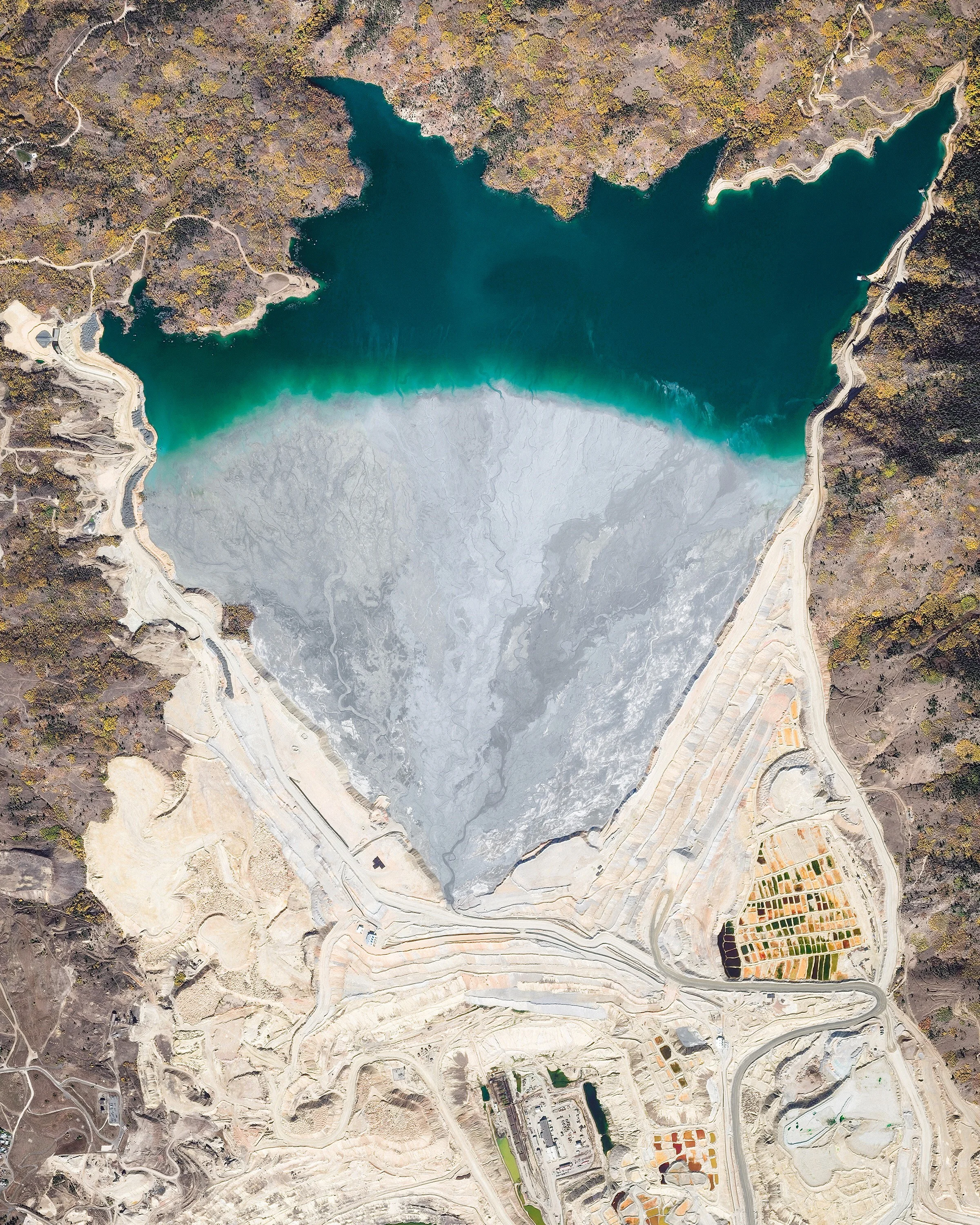 The Yankee Doodle Tailings Pond in Butte, Montana, is used as a dumping site for leftover materials from nearby copper mines. It covers an area of roughly 2.5 square miles (6.5 sq. km) and is contained by a 650-foot (200 m) tall earthen dam — one of the largest of its kind in the United States. To help offset the acidity of mine waste, lime rock is added to create a non-acidic tailings slurry. 46°02'37.3"N, 112°30'23.2"W Source imagery: DigitalGlobe