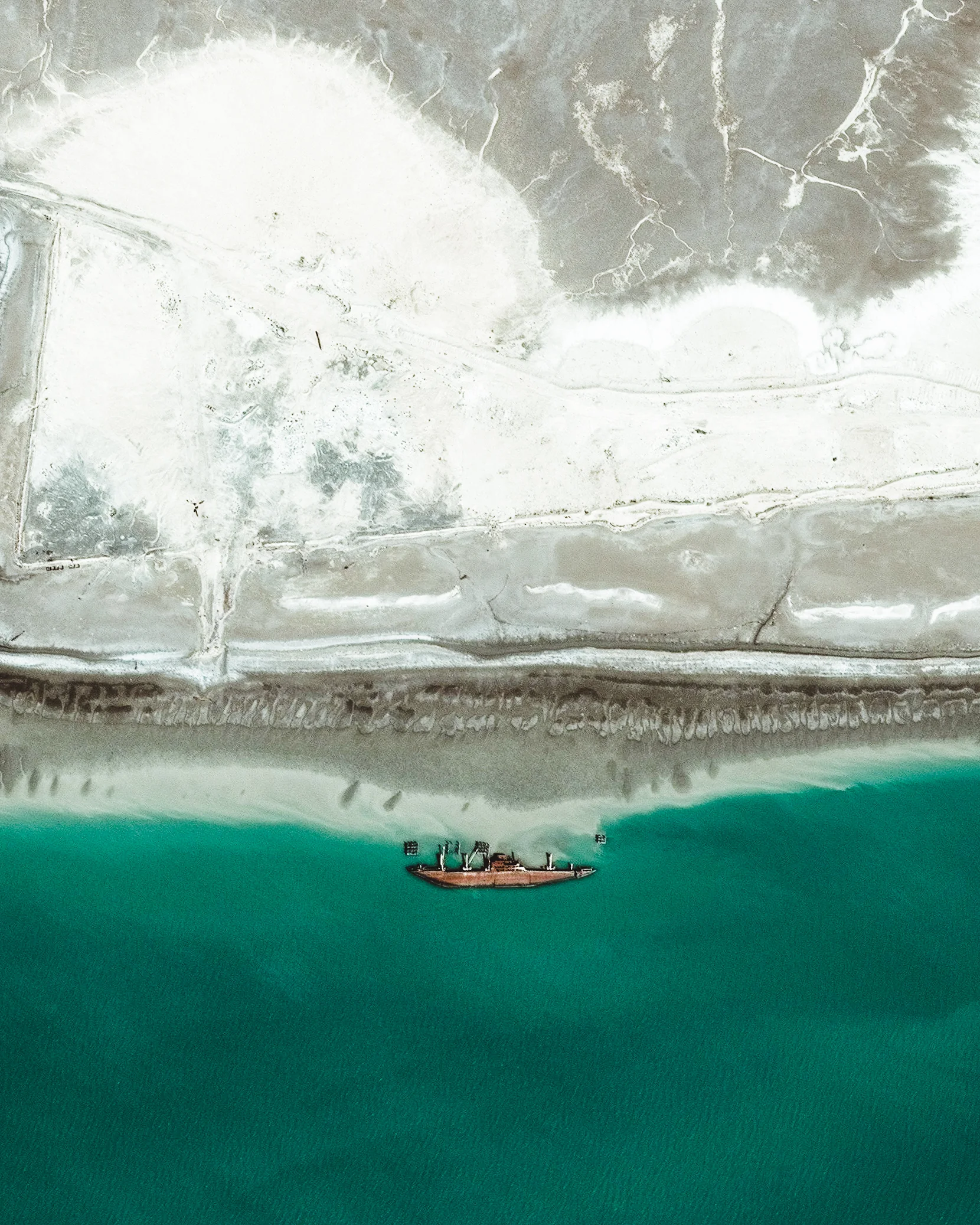 A large boat lies overturned in the Khawr Abd Allah estuary, near the city of Umm Qasr in southern Iraq. Since this waterway is close to Iraq’s borders with Kuwait and Iran, it has played an important role in regional conflicts, such as the Iran-Iraq War and the First Gulf War. 30°00'05.5"N, 47°59'42.3"E Source imagery: DigitalGlobe