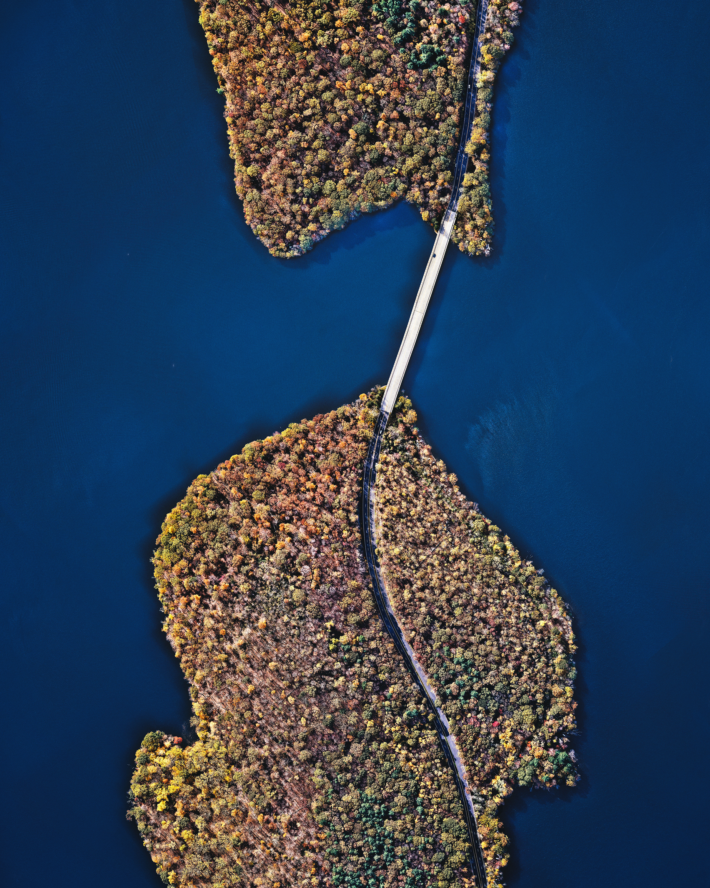 A bridge crosses the Kensico Reservoir in the town of Valhalla, New York. Located about 15 miles (24 km) north of New York City, the reservoir stores waters received from the Catskill Mountains and provides a site for fishing and boating recreation. With an average depth of nearly 44 feet (13.5 m) and a maximum depth of 120 feet (37 m), it can hold 30 billion gallons (113 billion liters) of water. 41°05'56.0"N, 73°44'42.7"W Source imagery: Nearmap