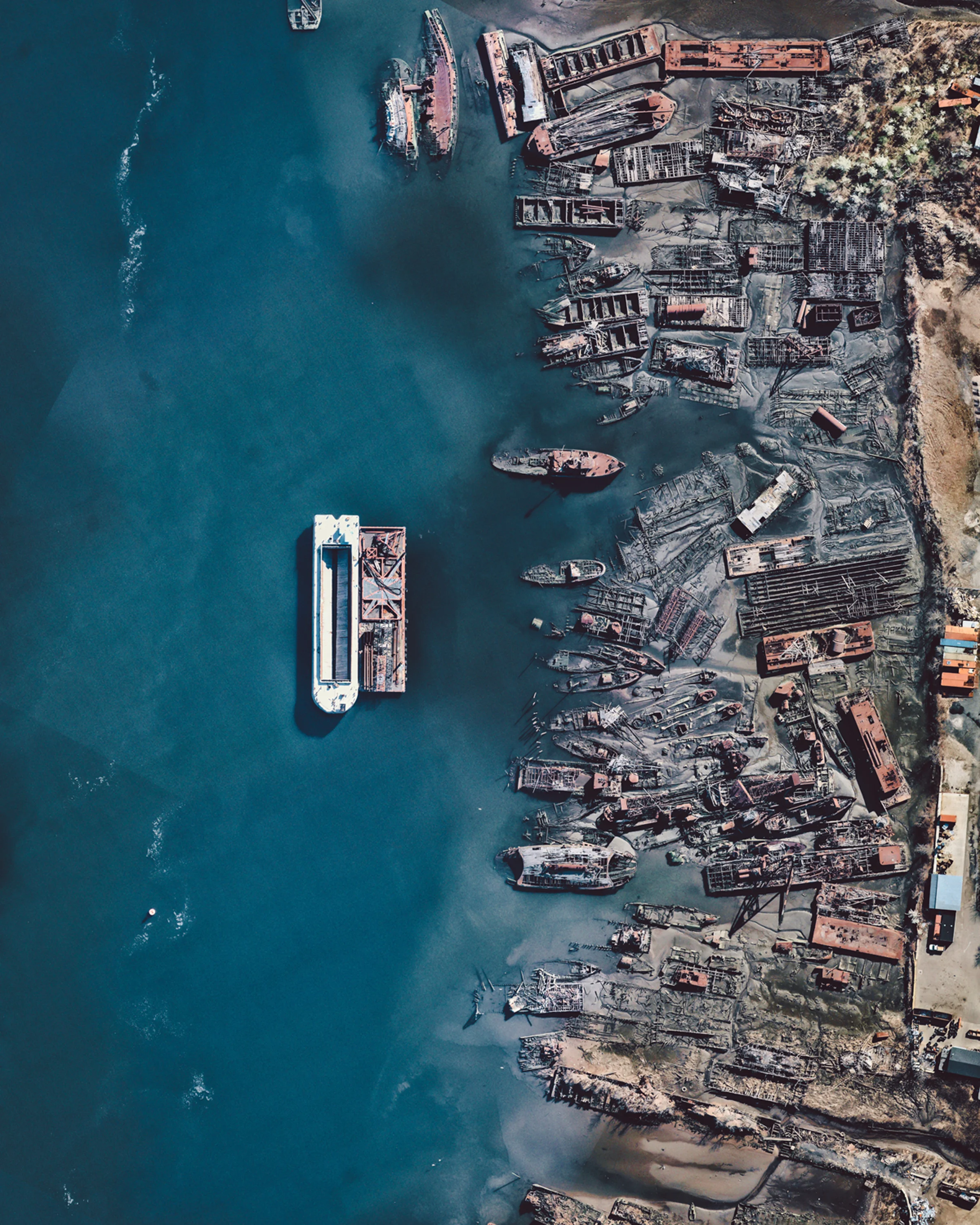 The “Staten Island Boat Graveyard” is a marine scrapyard located in Arthur Kill on the northern shore of Staten Island, New York. Founded in the 1930s, it serves as a dumping ground for wrecked tugboats, barges, ferries and other vessels from all decades of the 20th century. Some of these boats have historic significance, including the submarine chaser USS PC-1264, the first World War II U.S. Navy ship to have a predominantly African-American crew and the New York City Fire Department fireboat, Abram S. Hewitt, which served as the floating command post at the 1904 sinking of the passenger ferry PS General Slocum, a disaster that killed more than 1,000 people. 40°33'24.9"N, 74°12'55.9"W Source imagery: Nearmap