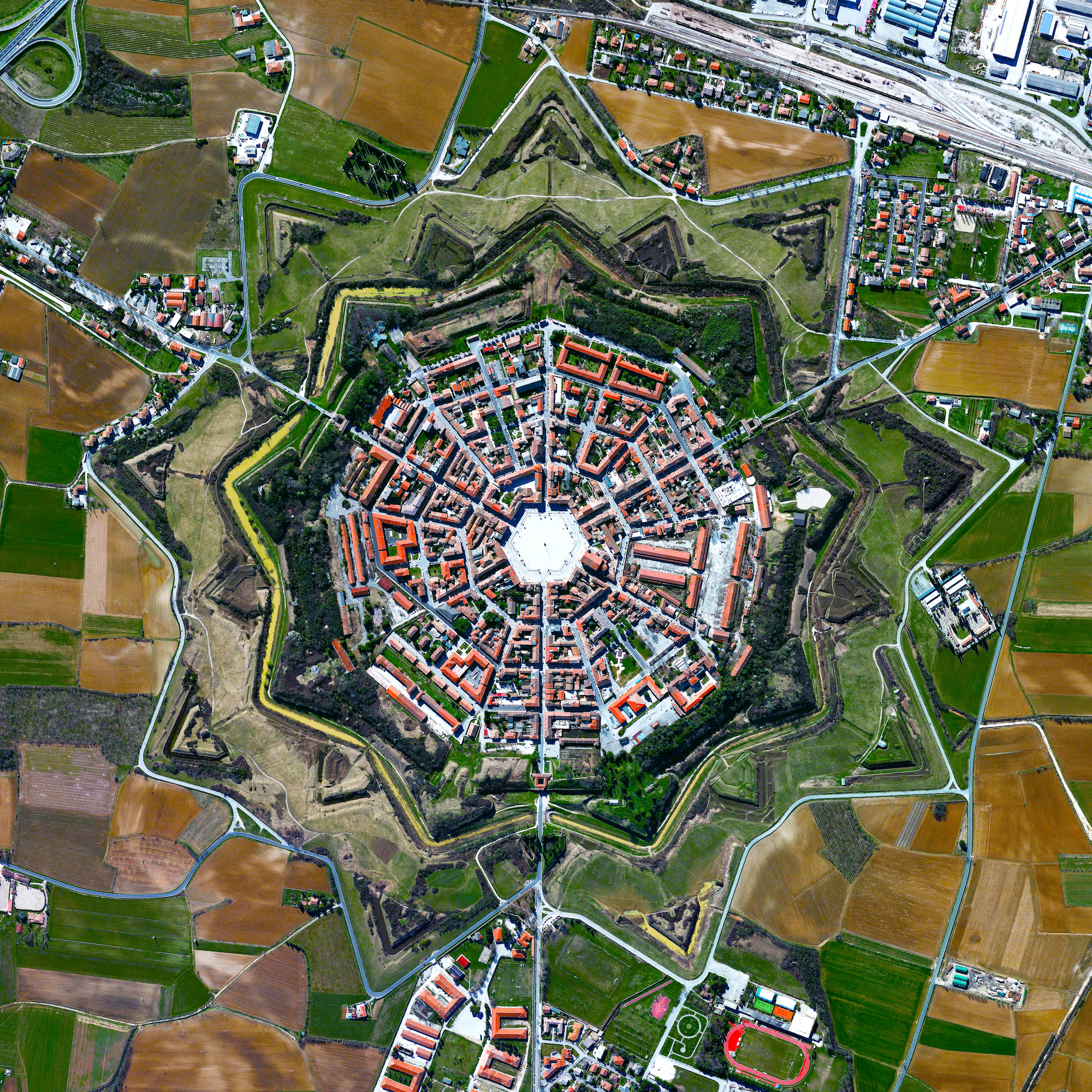 The town of Palmanova, Italy, is recognized by its concentric layout known as a “star fort.” The rationale for this construction was that an attack on any individual wall could be defended from the two adjacent star points by shooting the enemy from behind. The three rings that surround Palmanova were completed in 1593, 1690, and 1813. 45°54'17.8"N, 13°18'35.8"E Source imagery: DigitalGlobe
