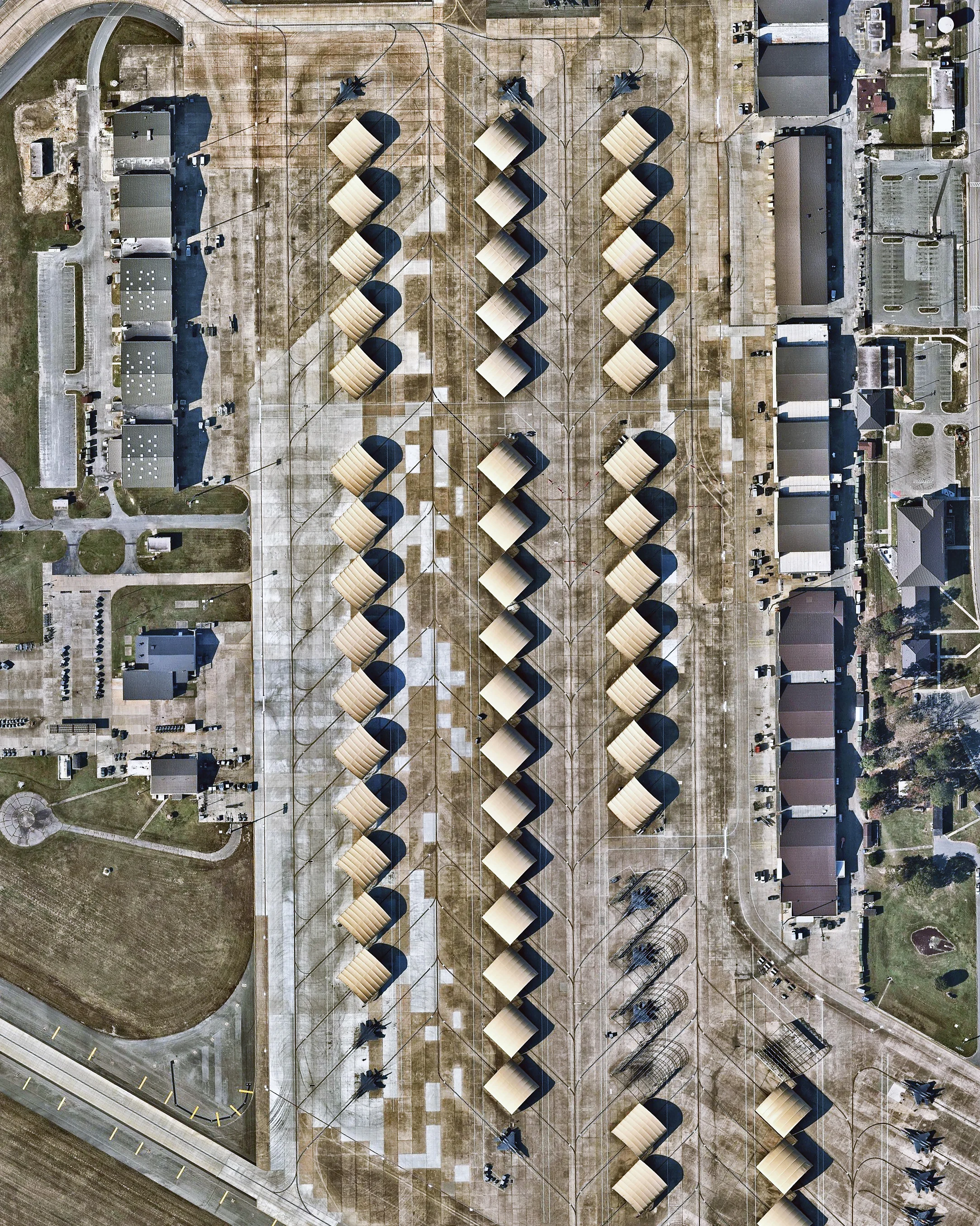 Planes sit under coverings on the tarmac of Seymour Johnson Air Force Base in Goldsboro, North Carolina. The base was established in June 1942 and served as a training facility throughout World War II before it was deactivated in May 1946. Since reopening as a Tactical Air Command Base in 1956, it has been home to B-52 bombers, KC-10 and KC-135 tankers, and F-4 and F-16 fighters. 35°21'03.6"N, 77°57'46.8"W Source imagery: Nearmap