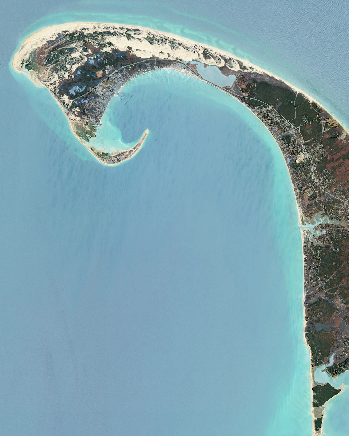Cape Cod is a hook-shaped peninsula that extends into the Atlantic Ocean off southeastern Massachusetts, USA. The 15 towns on the cape are a popular summer destination with quaint villages, seafood shacks, lighthouses, and many beaches. The three towns at the northernmost tip of the cape — Wellfleet, Truro, and Provincetown — are visible in this Overview. 42.058°N, 70.179°W Source imagery: DigitalGlobe