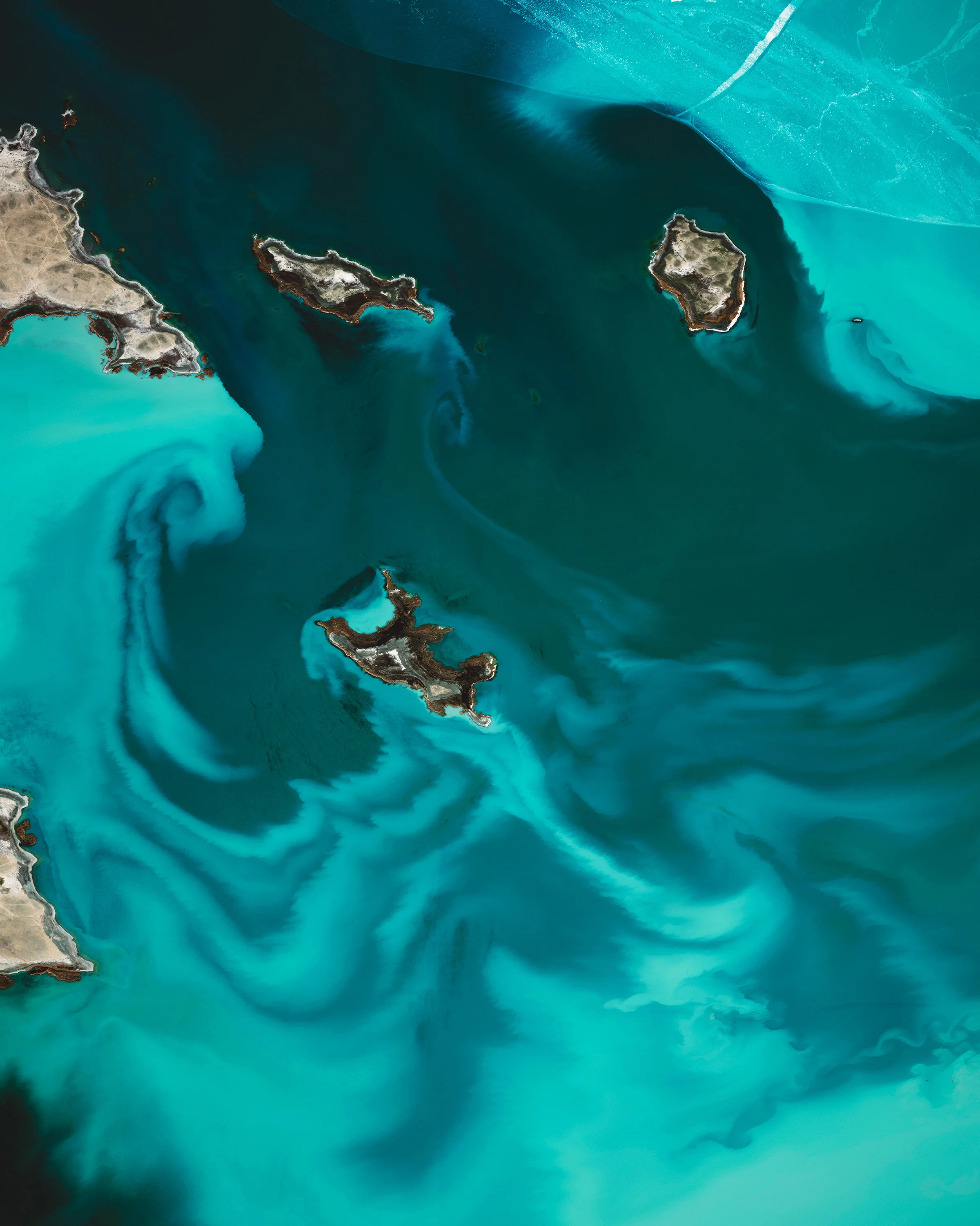 Alakol Lake is a 1,020-square-mile (2,650 sq. km) salt lake located in east central Kazakhstan. The lake, which aptly translates to "multicolored lake," has varying shades of blue and green depending on its depth, levels of phytoplankton, and sediments flowing in from rivers and streams. Its mineral-rich water and mud are believed to be therapeutic, attracting many visitors who seek a natural remedy for psoriasis and other skin ailments. 46°10'00.0"N, 81°35'00.0"E Source imagery: DigitalGlobe