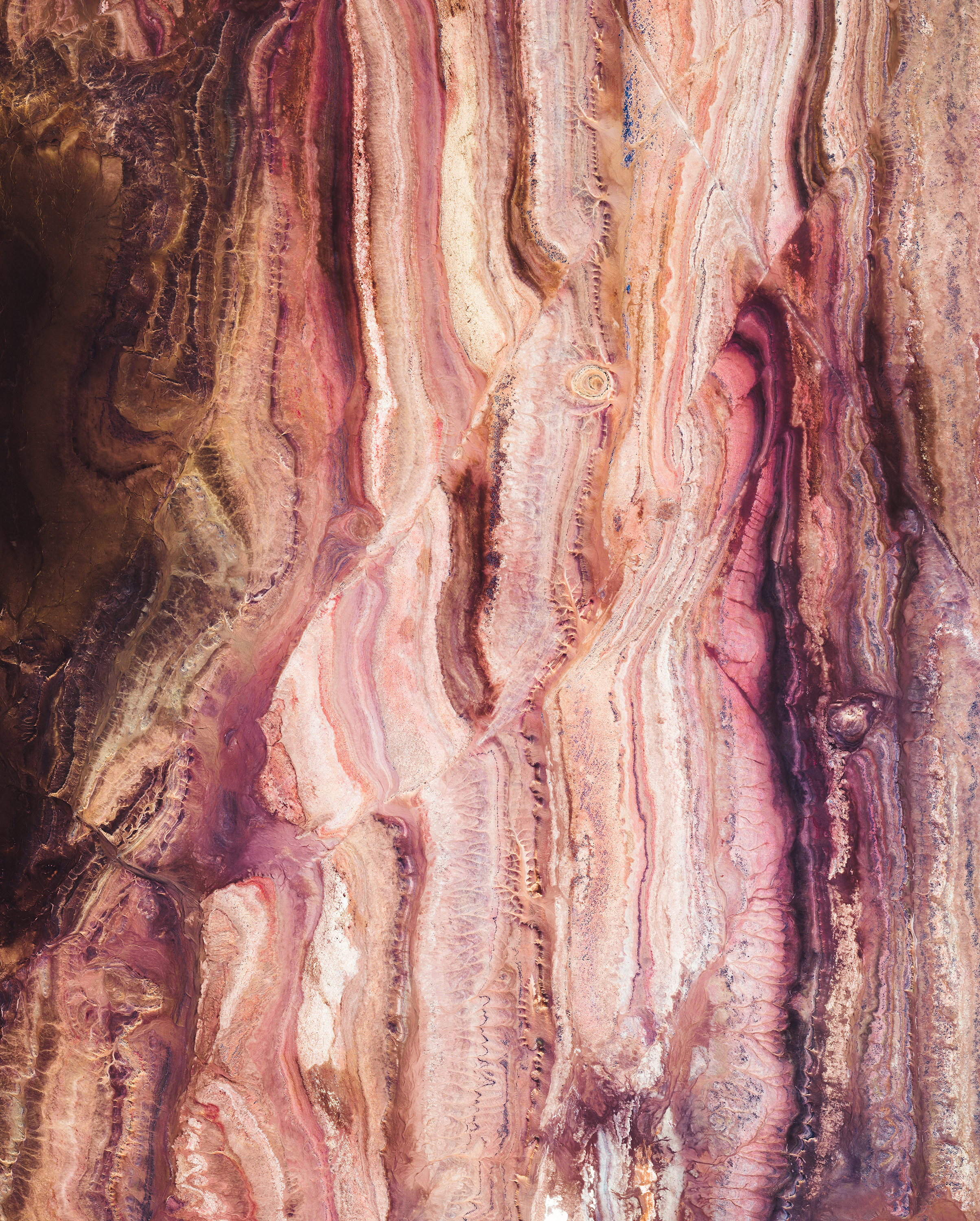 This Overview shows colorful rock formations in the Sahara Desert, west of the town of Reggane, Algeria. The climate in this region is torrid and almost rainless, with an average annual rainfall of less than 0.4 inches (10 mm). In the summer, daytime temperatures are known to consistently reach 122°F (50°C), earning this area its nickname — the “triangle of fire.” 25°11'32.6"N 3°23'21.3"W Source imagery: Maxar Technologies