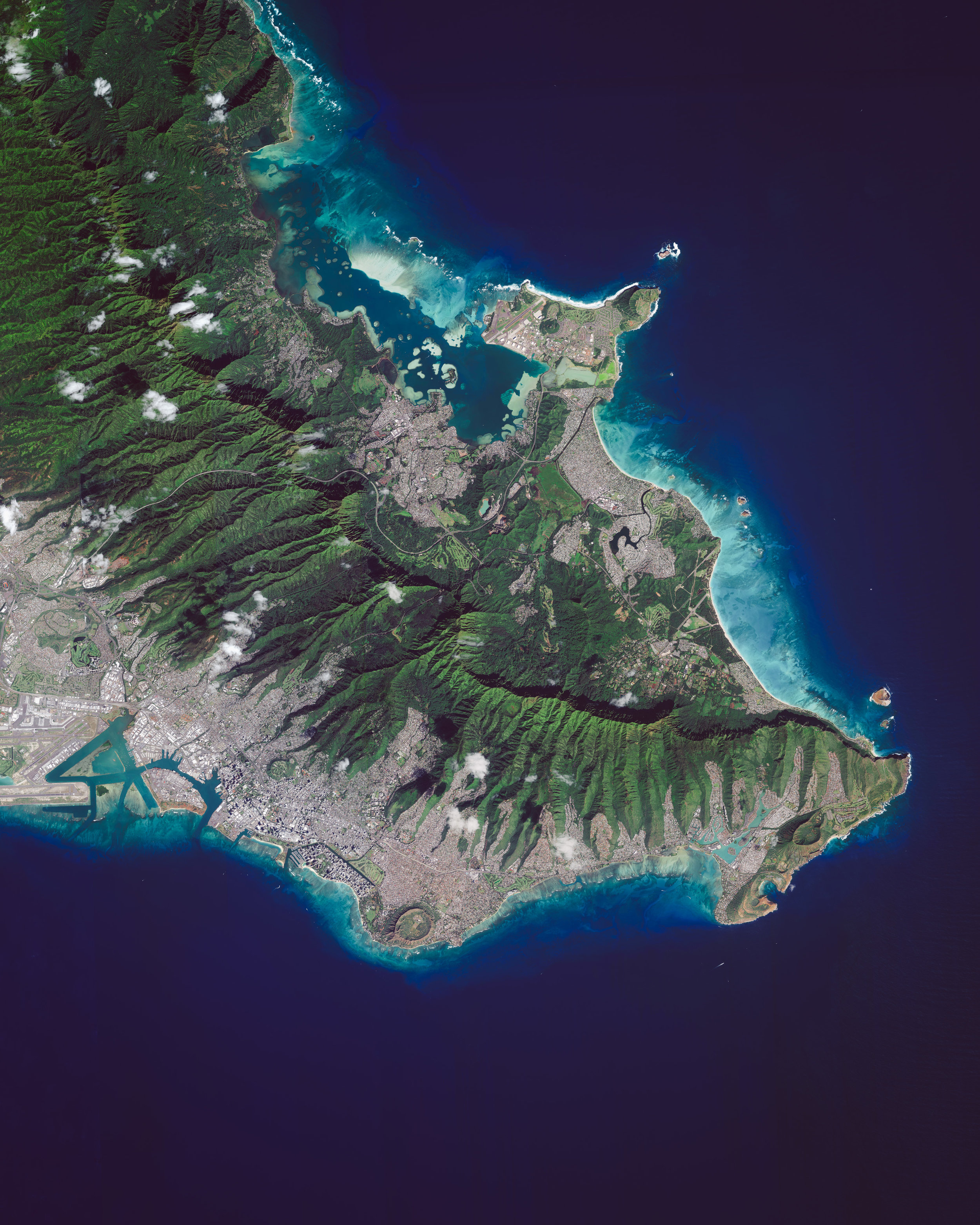 Honolulu is the capital and largest city in the U.S. state of Hawaii. Located along the southeastern coast of Oahu Island, it is the most remote city of its size in the world. The Honolulu Volcanic Series is partially located inside the city, and Diamond Head — a prominent volcanic cone — is visible in this Overview along the southern coast. 21°18'00.0"N 157°49'00.0"W Source imagery: Maxar Technologies