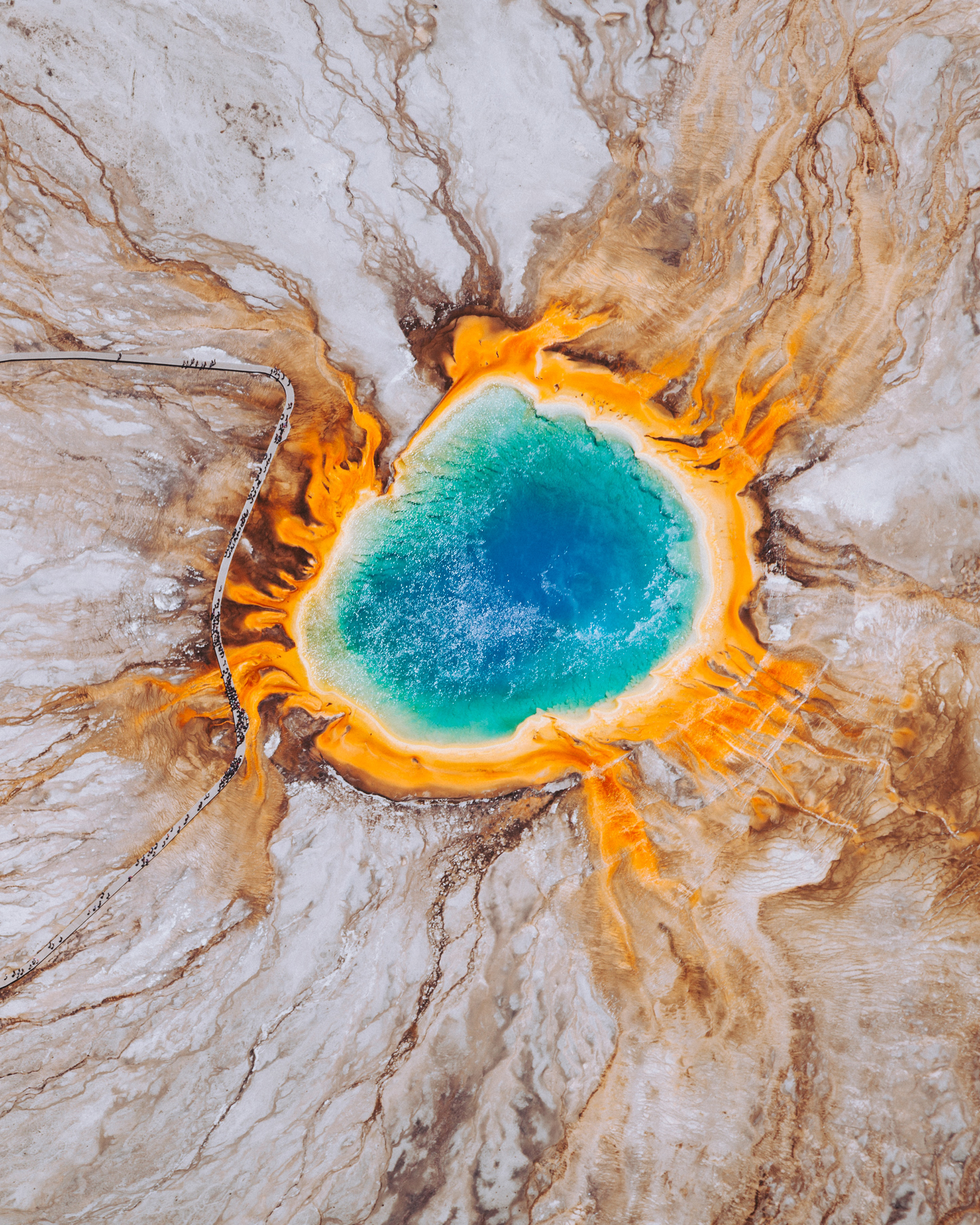 The Grand Prismatic Spring — located in Teton County, Wyoming, inside Yellowstone National Park — is the largest hot spring in the United States and the third largest in the world. The spring is approximately 370 feet (110 m) in diameter, 160 feet (50 m) deep, and discharges an estimated 560 gallons (2,100 L) of water per minute. Its vivid colors, which match the rainbow dispersion of white light by a prism, are caused by layers of microorganisms that live around the edges of its mineral-rich water. 44.525029, -110.838155 Source imagery: Chris Leipelt