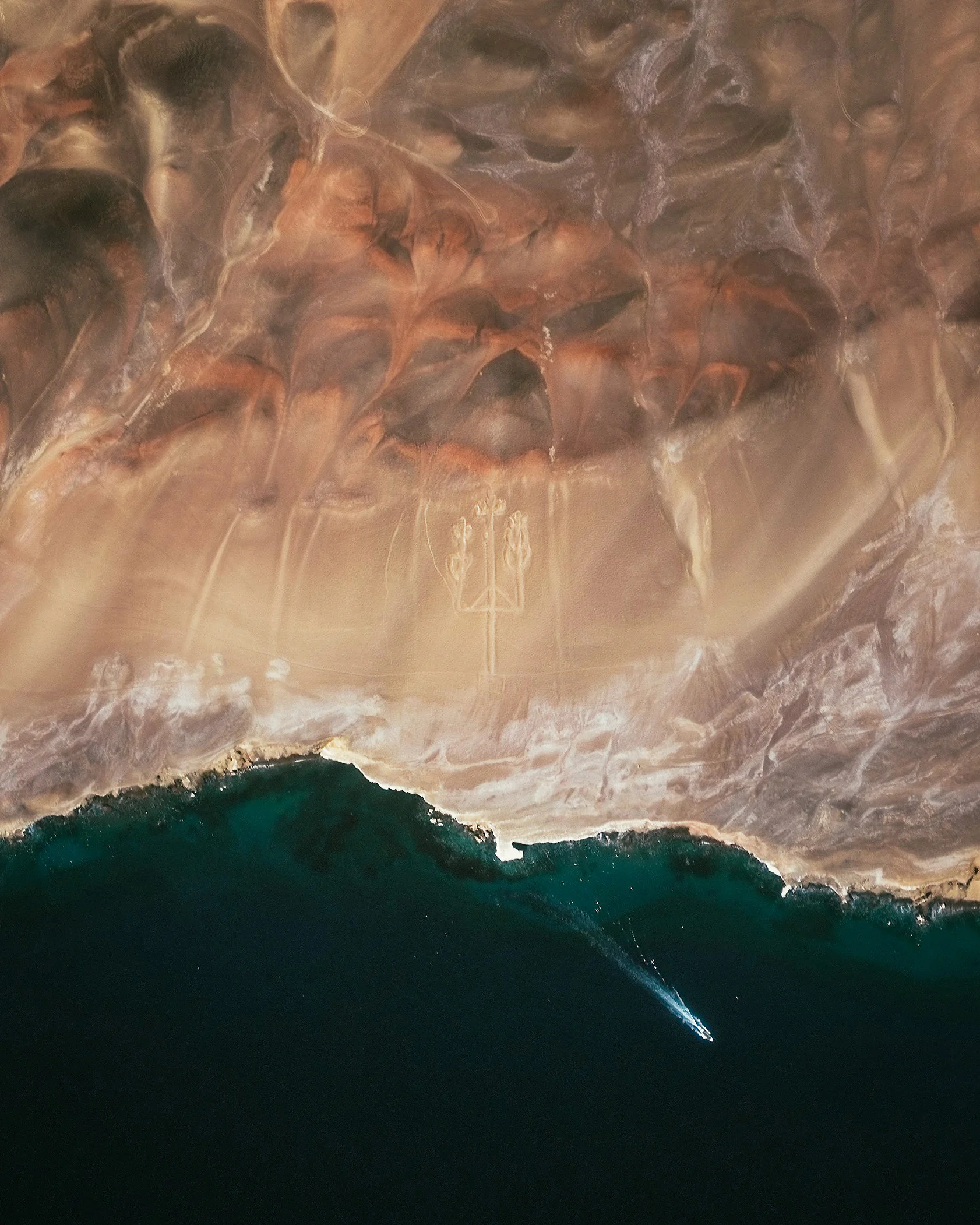 The Paracas Candelabra (also called the Candelabra of the Andes) is a prehistoric geoglyph found on the northern face of the Paracas Peninsula at Pisco Bay in Peru. The design, which may date back as far as 200 BCE, is cut two feet (0.6 m) into the soil and has stones placed around it. The figure is 595 feet (181 m) tall — large enough to be seen 12 miles (19.3 km) at sea. -13.794583°, -76.308697° Source imagery: Maxar Technologies