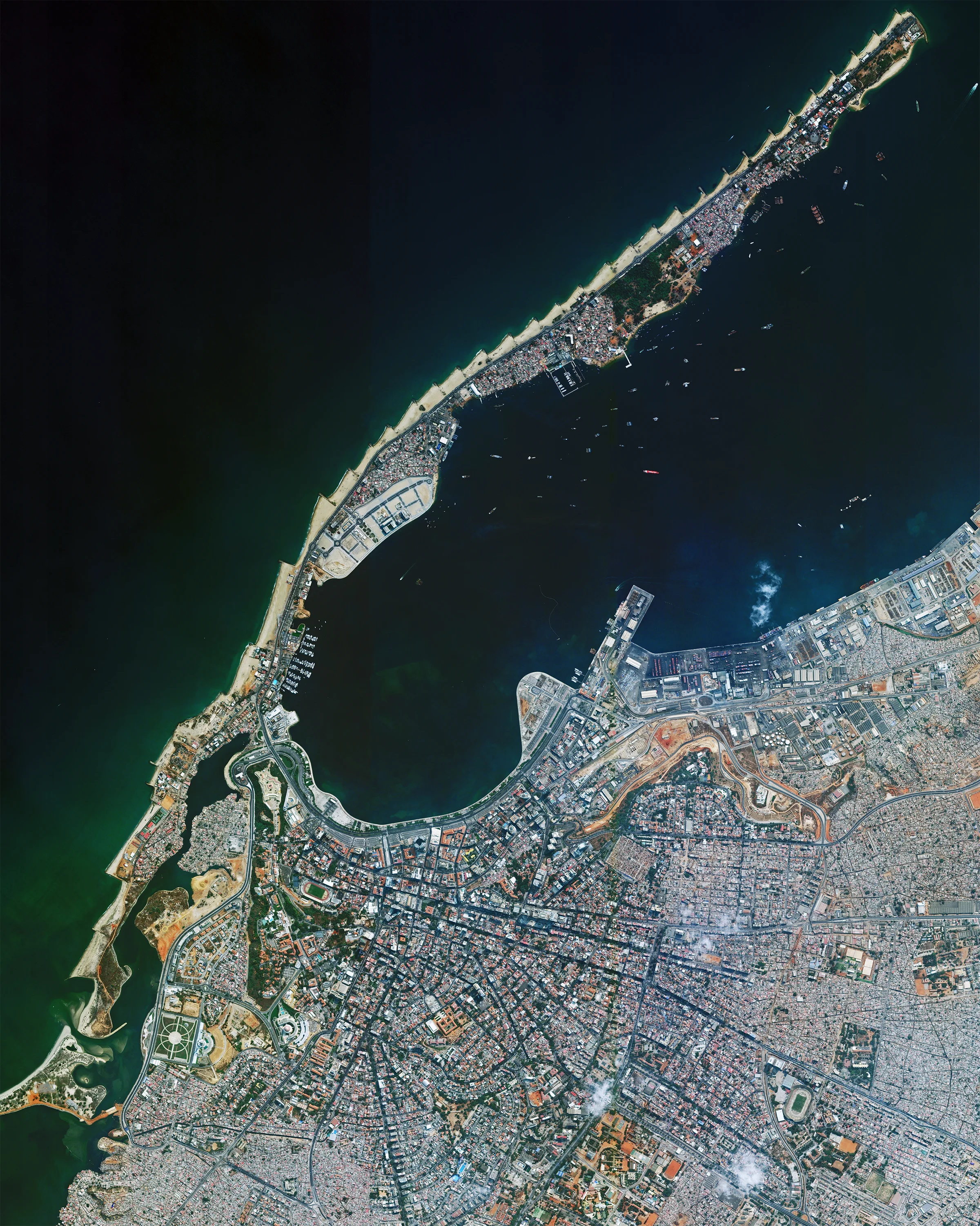 Luanda is the capital and largest city in Angola, located on the country’s northern coast with the Atlantic Ocean. With upwards of 8 million people in its metropolitan area, it is the most populous Portuguese-speaking capital city in the world. Ilha do Cabo (also known as Ilha de Luanda) is a spit that extends offshore the city, forming a natural harbor and providing a weekend getaway for many residents. -8.838333°, 13.234444° Source imagery: Maxar Technologies