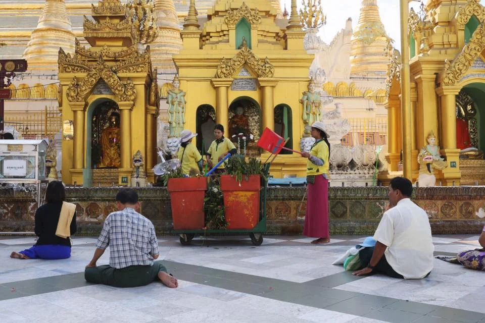Workers at Shwedagon Pagoda throw away offerings left by visitors. January 2017.