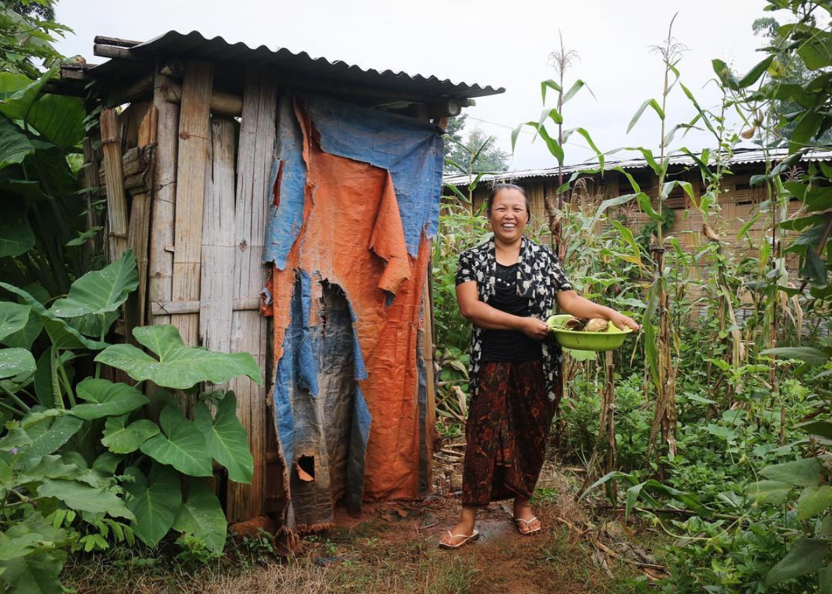 A Lisu IDP collects corns grown within her camp grounds. Northern Shan, Myanmar. July, 2018.