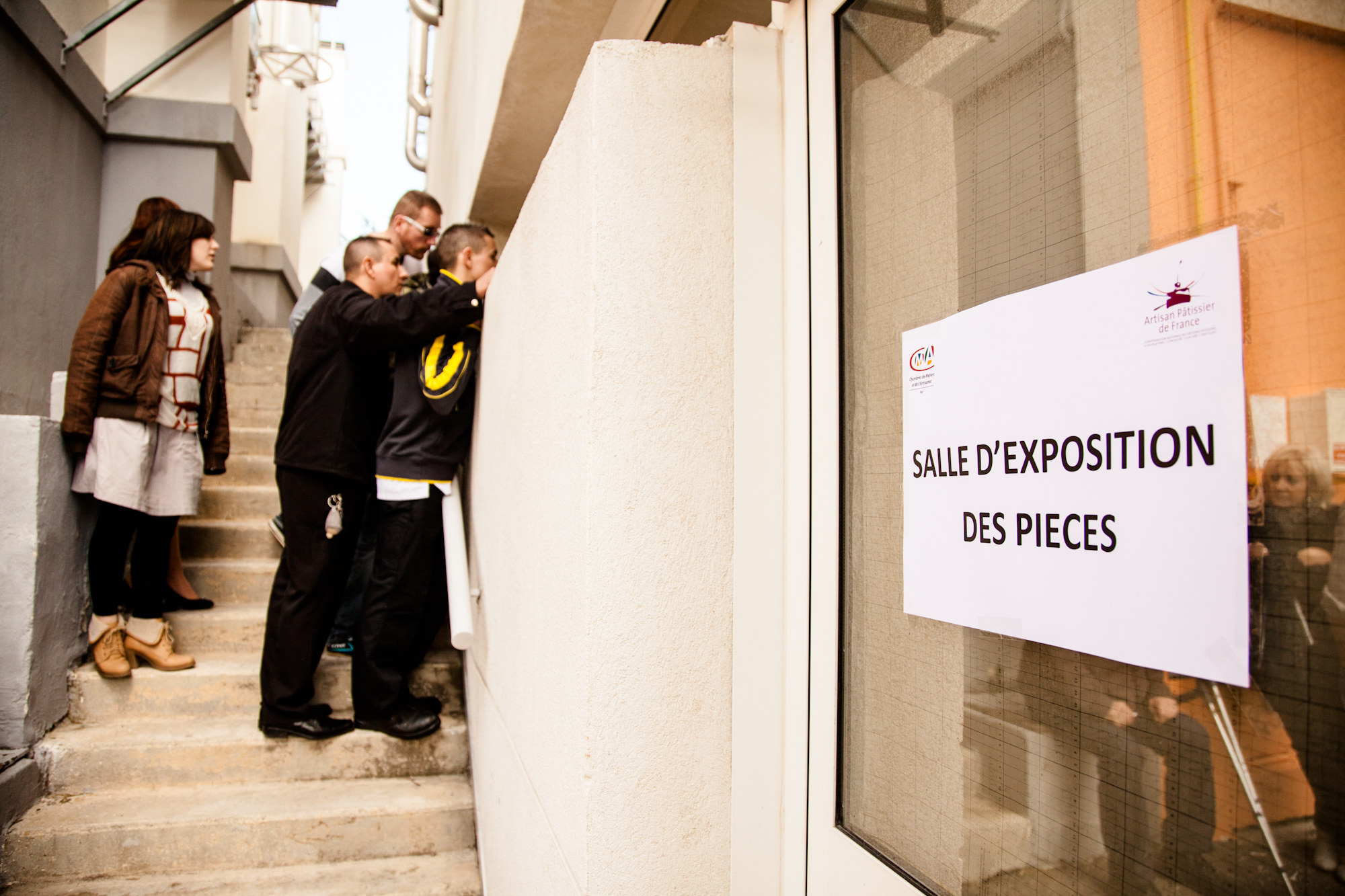  Pendant que le jury note les pièces et les buffets, les camarades de classe d'un des participants tentent d'apercevoir son travail. 