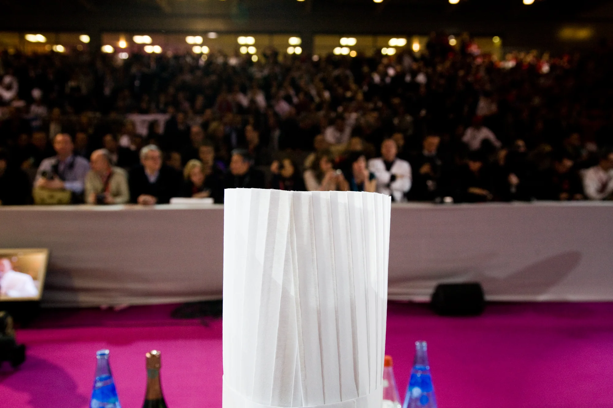 A midi, le jury, composé de 24 chefs internationalement reconnus, prend place à la table. La tribune, comme dans un stade, s'est elle-même remplie. 2000 spectacteurs et supporteurs assisteront aux 2 jours de spectacle.