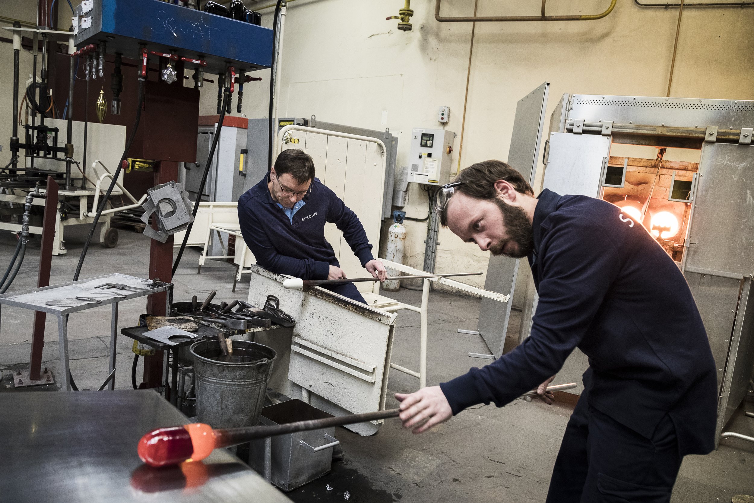  Saint-Louis-lès-Bitche, 5 décembre 2016. Xavier Zimmermann, (à gauche), verrier, au travail avec Steve, à qui il transmet les gestes de la fabrication du presse-papier en cristal,  dans les ateliers de la cristallerie Saint-Louis. 