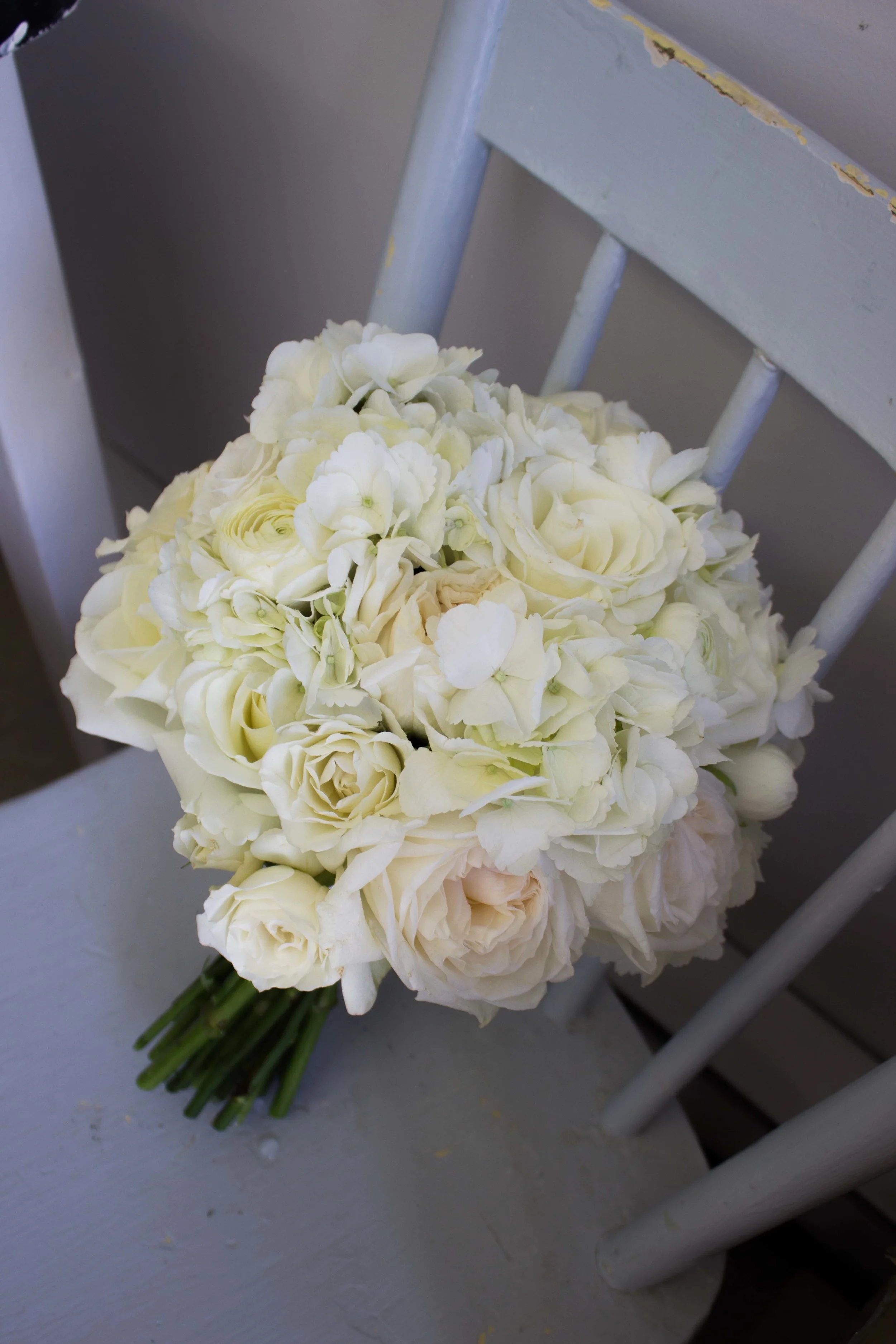 Classic white bouquet with hydrangea, roses, ranunculus, and lisianthus. 
