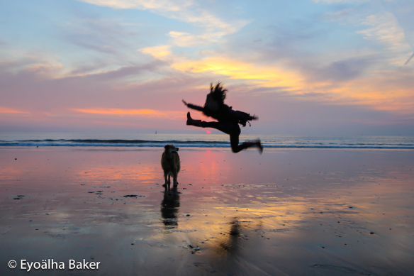 Honeybee jumping for joy with the setting sun and Molly dog at Marina Del Ray Beach, California.