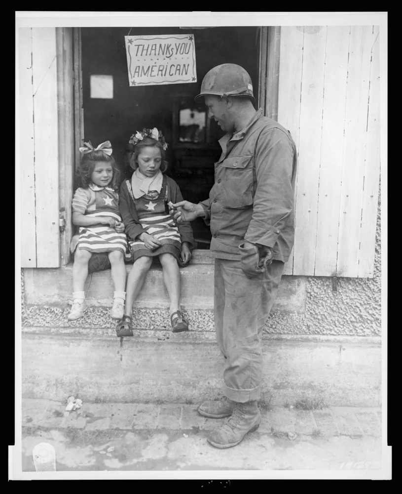 Sgt. Walter P. Goworek treats two little French lasses with some G.I. candy - July 4, 1944
