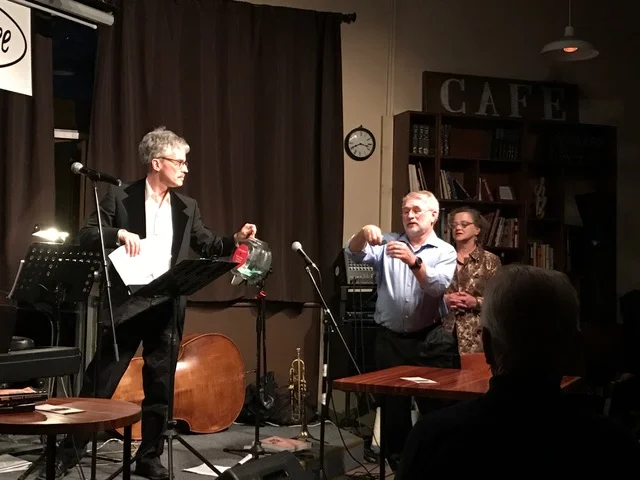 While Mary Beth Revak looks on, emcee Bob DuCharme waits for Brad Sayler to read the winner's name off a raffle ticket for one of the many wonderful prizes donated by the generous Charlottesville businesses listed above.