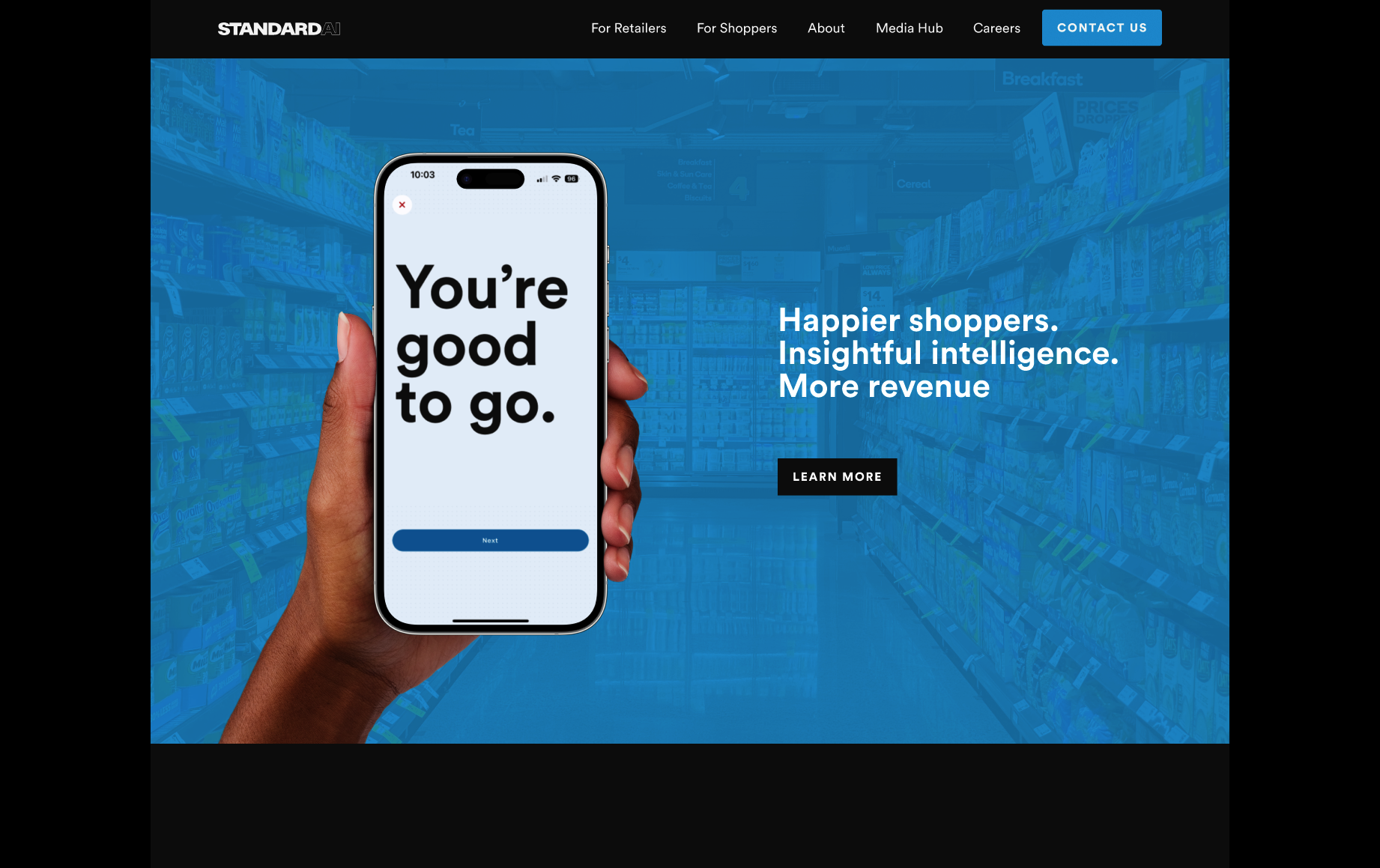 A computer screen showing a website homepage for Standard AI with a background of store shelves filled with cereal boxes and a hand holding a smartphone displaying the message 'You're good to go.'