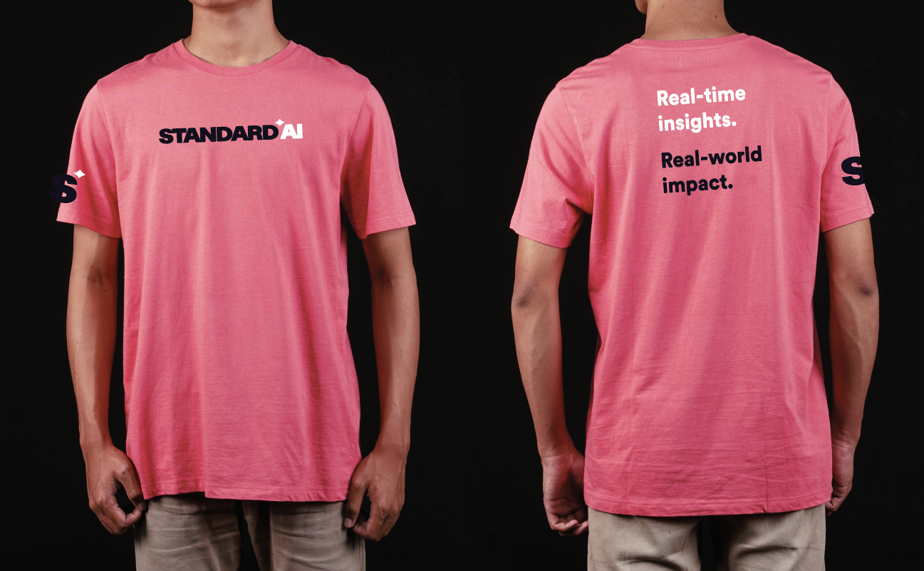 Front and back view of a person wearing a pink T-shirt with the text 'STANDARD AI' on the front and additional text on the back that reads 'Real-time insights. Real-world impact.'