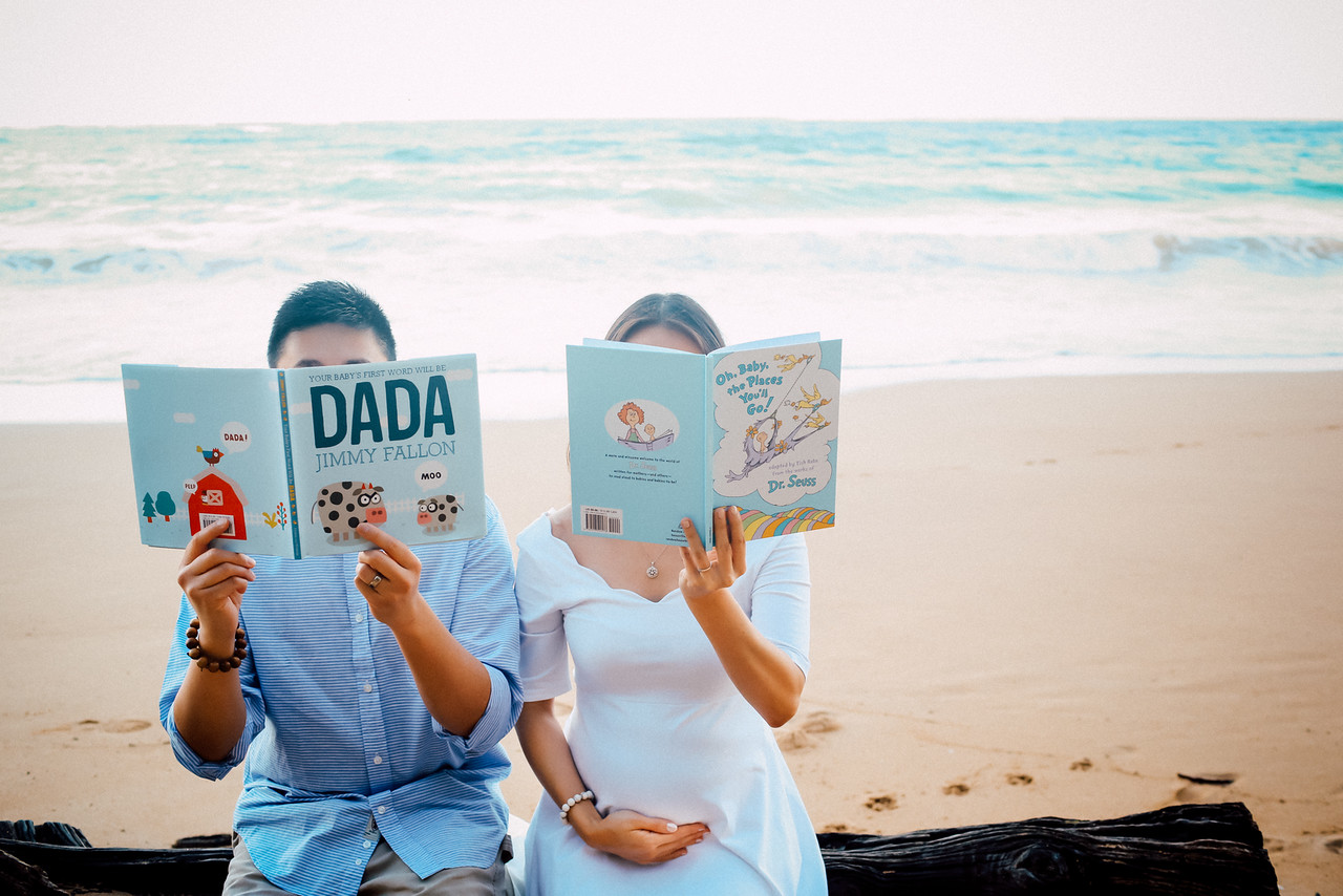 Babymoon couple on beach reading books