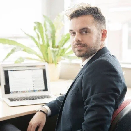 Business professional sitting at desk with laptop and plant