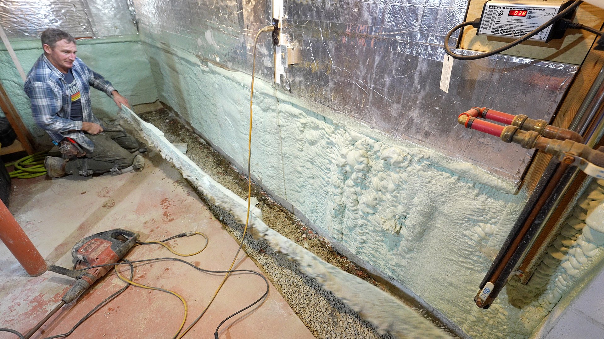 cutting spray foam insulation off a foundation wall