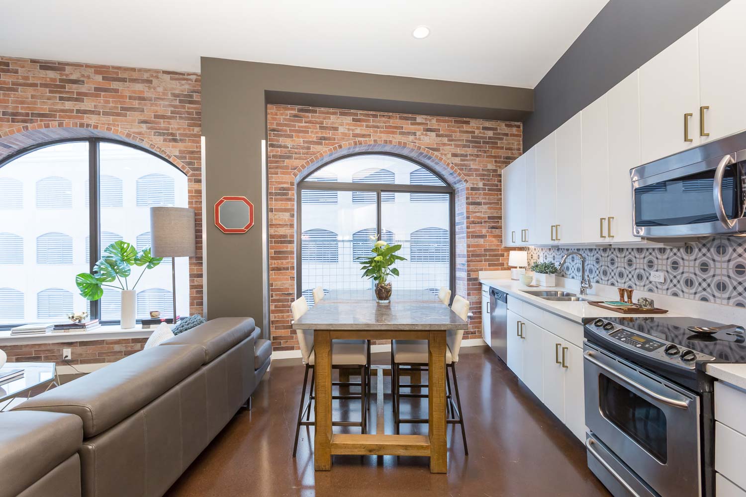 A counter-height island/dining table was added to add room for food prep or dining. We love the bold, patterned backsplash. The gray, black and white compliment the gold pulls and freshly painted white cabinets. The bold pattern contrasts the brick. 