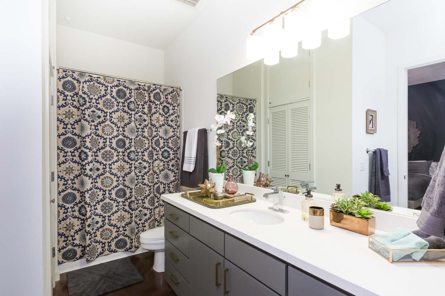 The bathroom simply received a new light fixture, bold shower curtain, and gray paint with gold pulls for the cabinets. 
