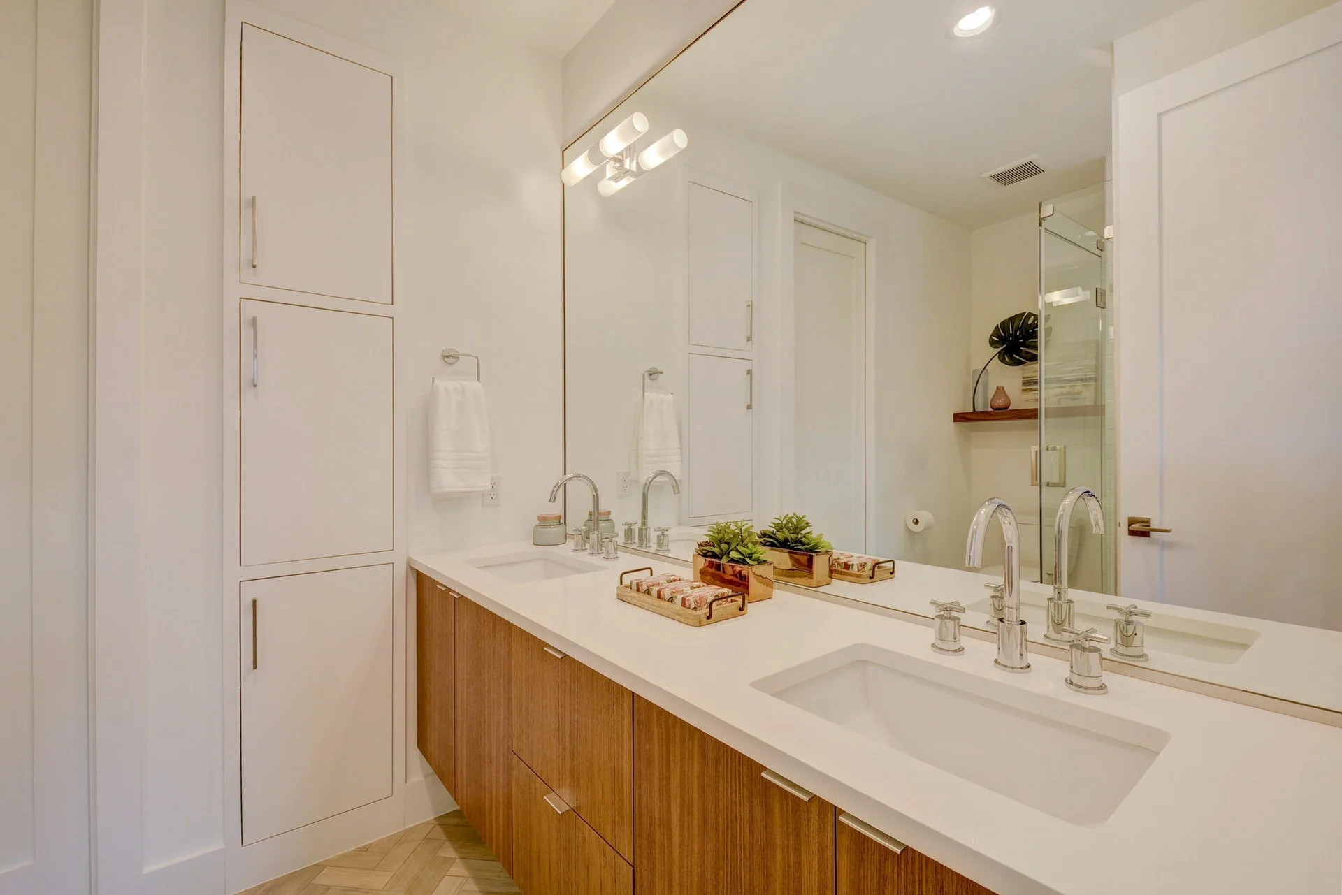 The second master bathroom includes white quartz countertops, cross bar faucets, and walnut cabinets. 
