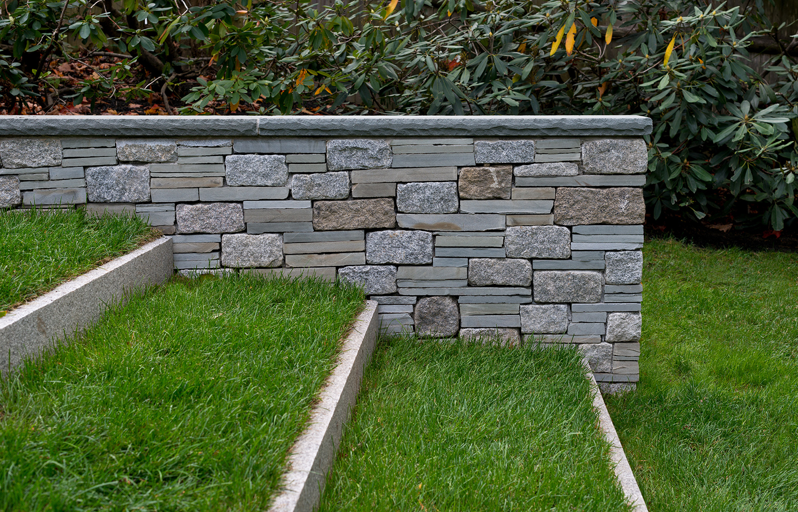 Our clients asked us to build grass and granite steps set on edge. The steps are enhanced with a cobble and bluestone cheek wall.