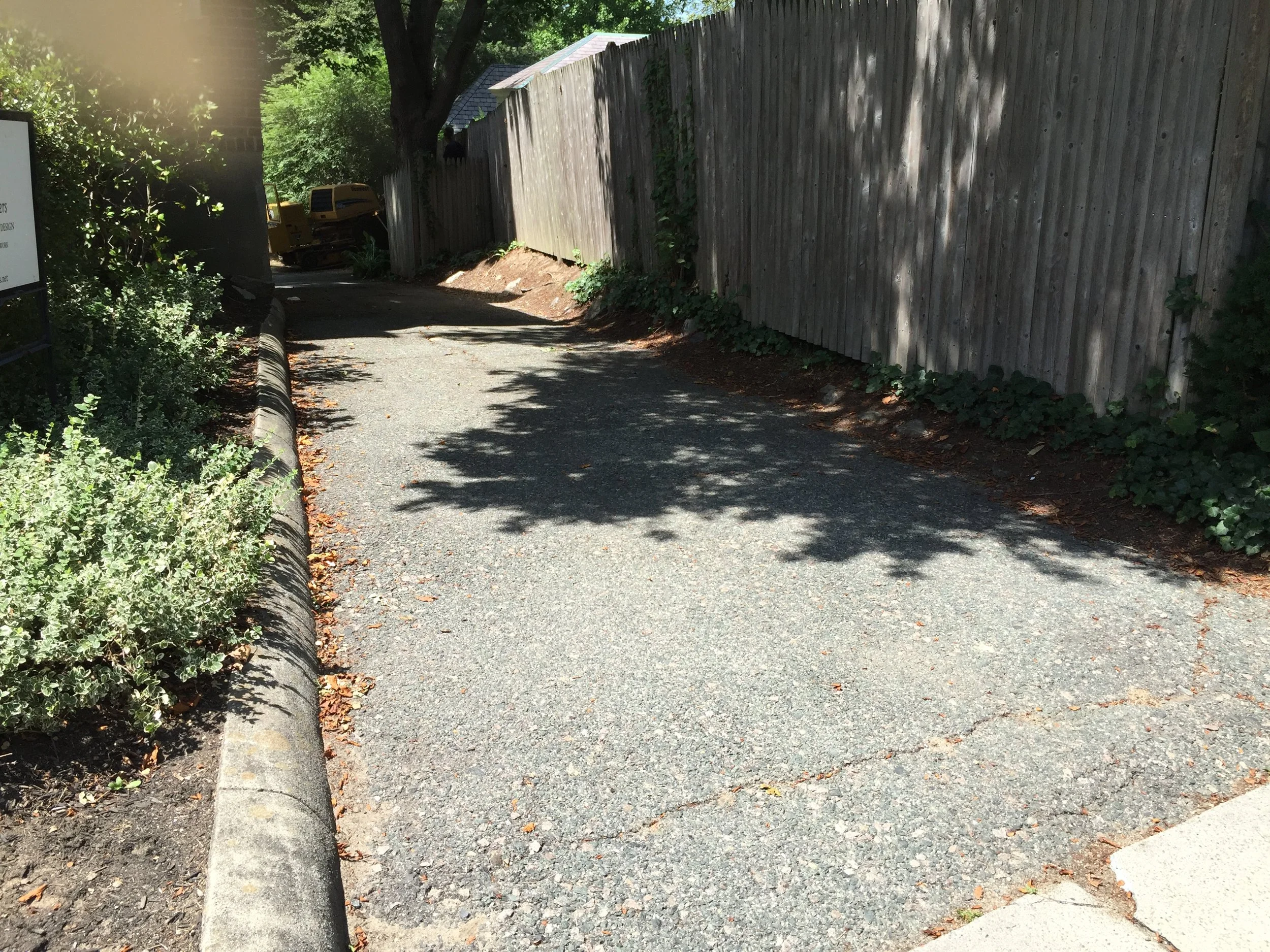  To update the drive, we first removed the old asphalt driveway and curb. We replaced it with our signature walls bluestone and cobble retaining walls that give the illusion of a dry-wall installation while actually being reinforced with mortar. New 