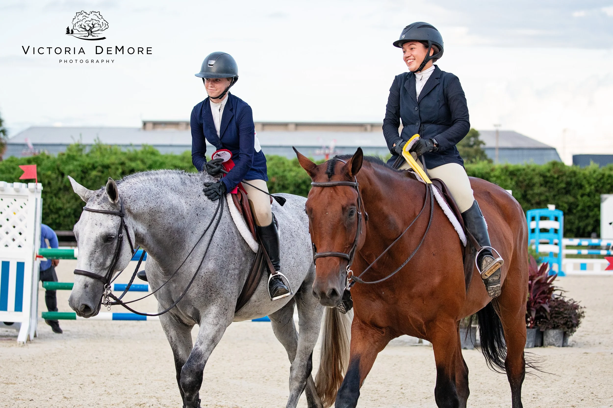 Two equestrians with ribbons exiting the arena.