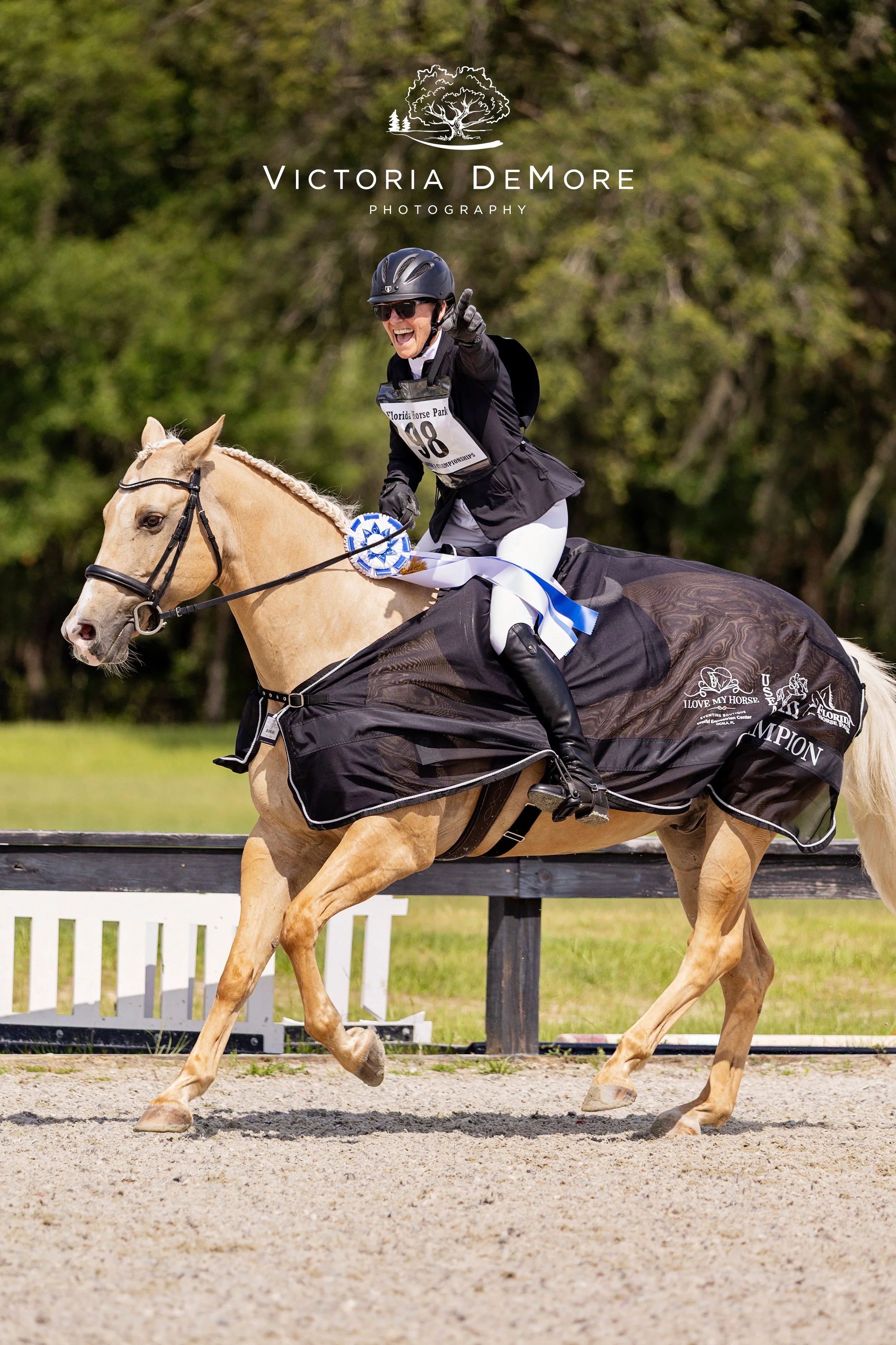 Rider with huge smile celebrating after winning an eventing championship. On a palomino horse.