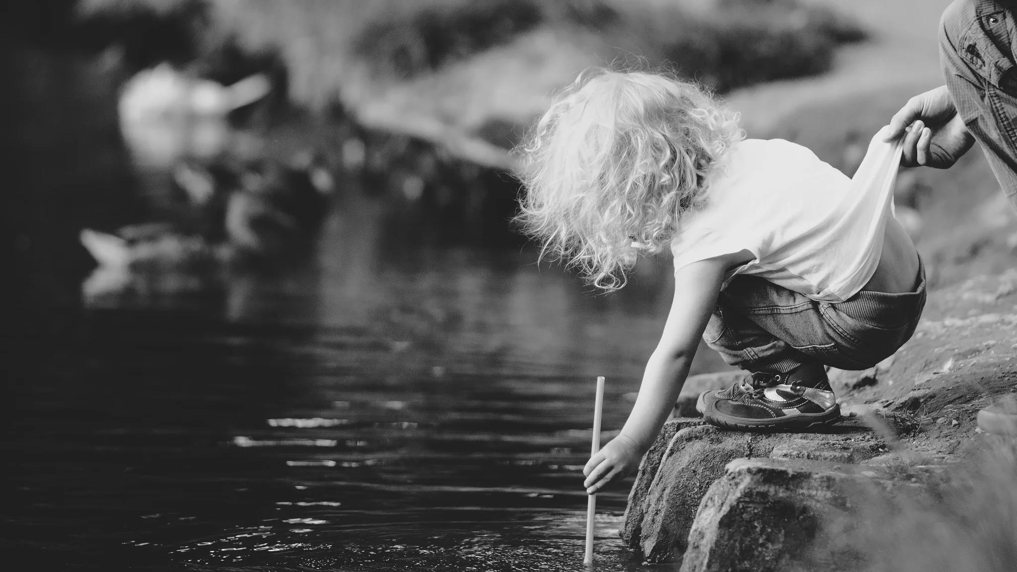 La seguridad ante todo: una mano adulta sujeta a un niño que juega al borde del río. Safety First , por Lukas Kr ., CC BY-NC 2.0 .