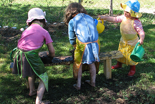 Niñas jugando afuera con la tierra, el agua, las plantas.